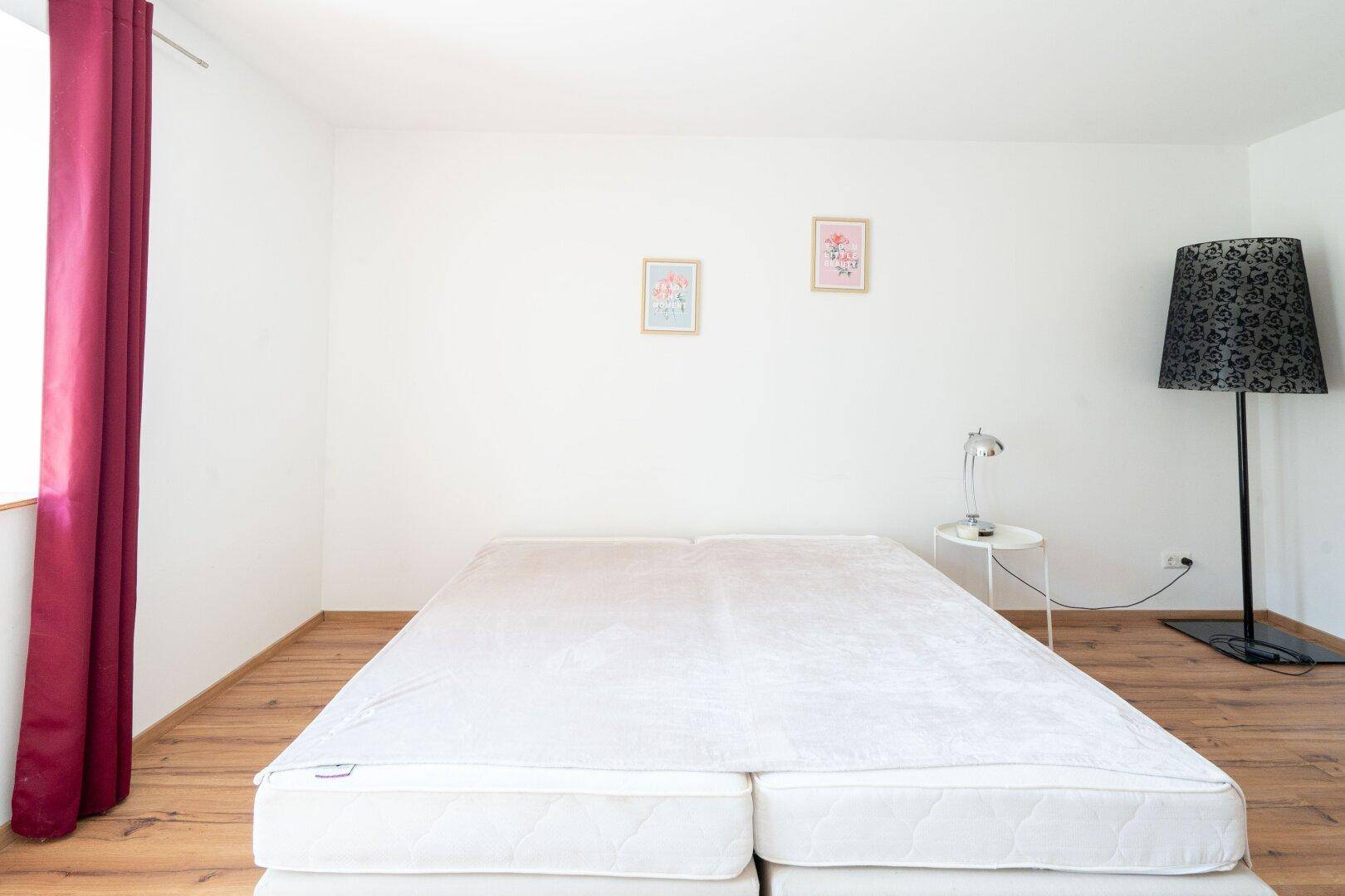 Helles Schlafzimmer mit Doppelbett und Holzboden, das eine ruhige und entspannende Umgebung bietet.