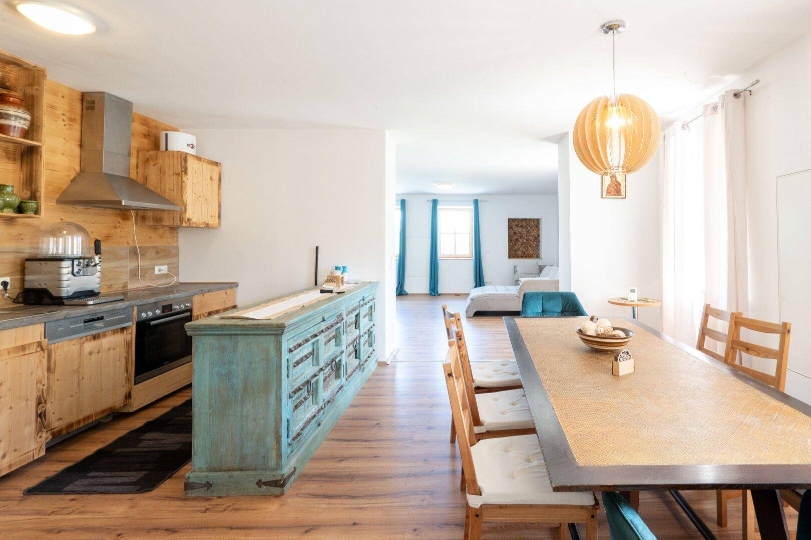 Geräumige Holzküche mit Essbereich und Blick in den angrenzenden Wohnbereich, ideal für Familien.