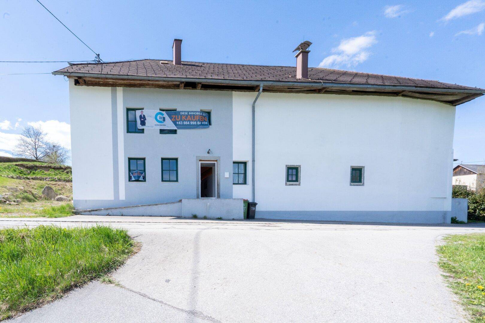 Fassade eines Gebäudes mit Werbeschild und mehreren Fenstern unter strahlend blauem Himmel.