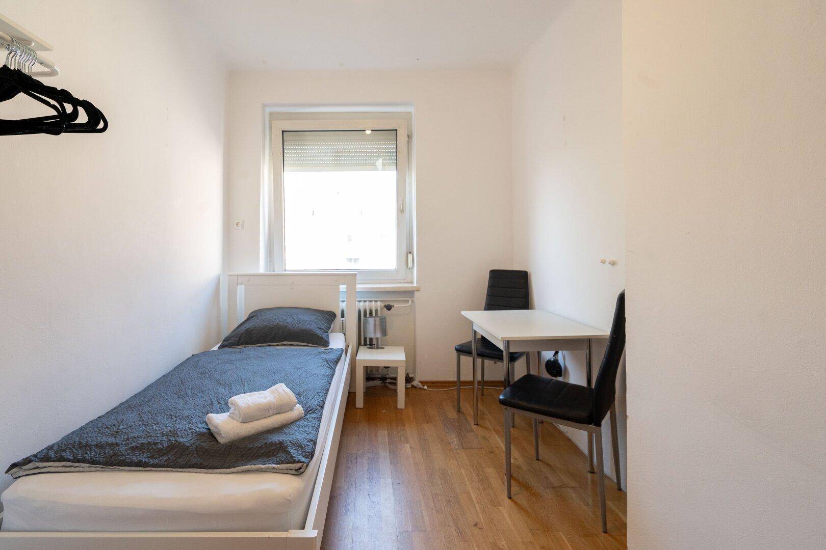 Gemütliches Schlafzimmer mit Einzelbett, Schreibtisch und Holzfußboden.
