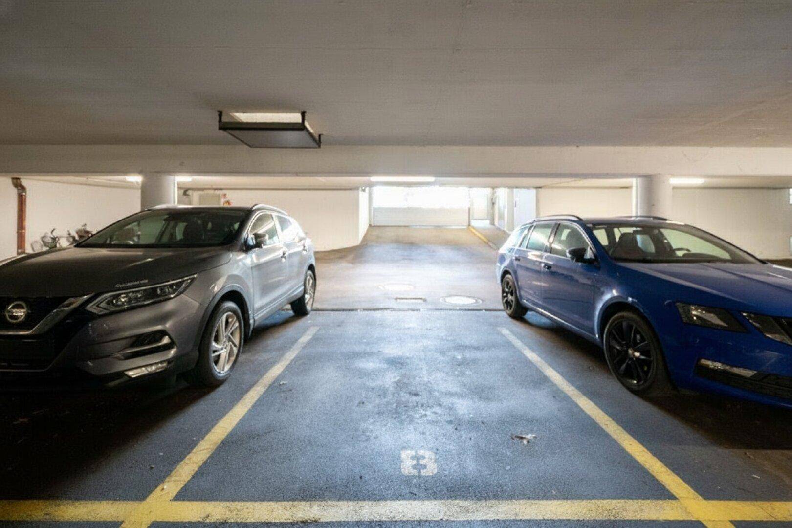 Tiefgarage mit markierten Stellplätzen und ausreichend Platz für zwei Fahrzeuge.