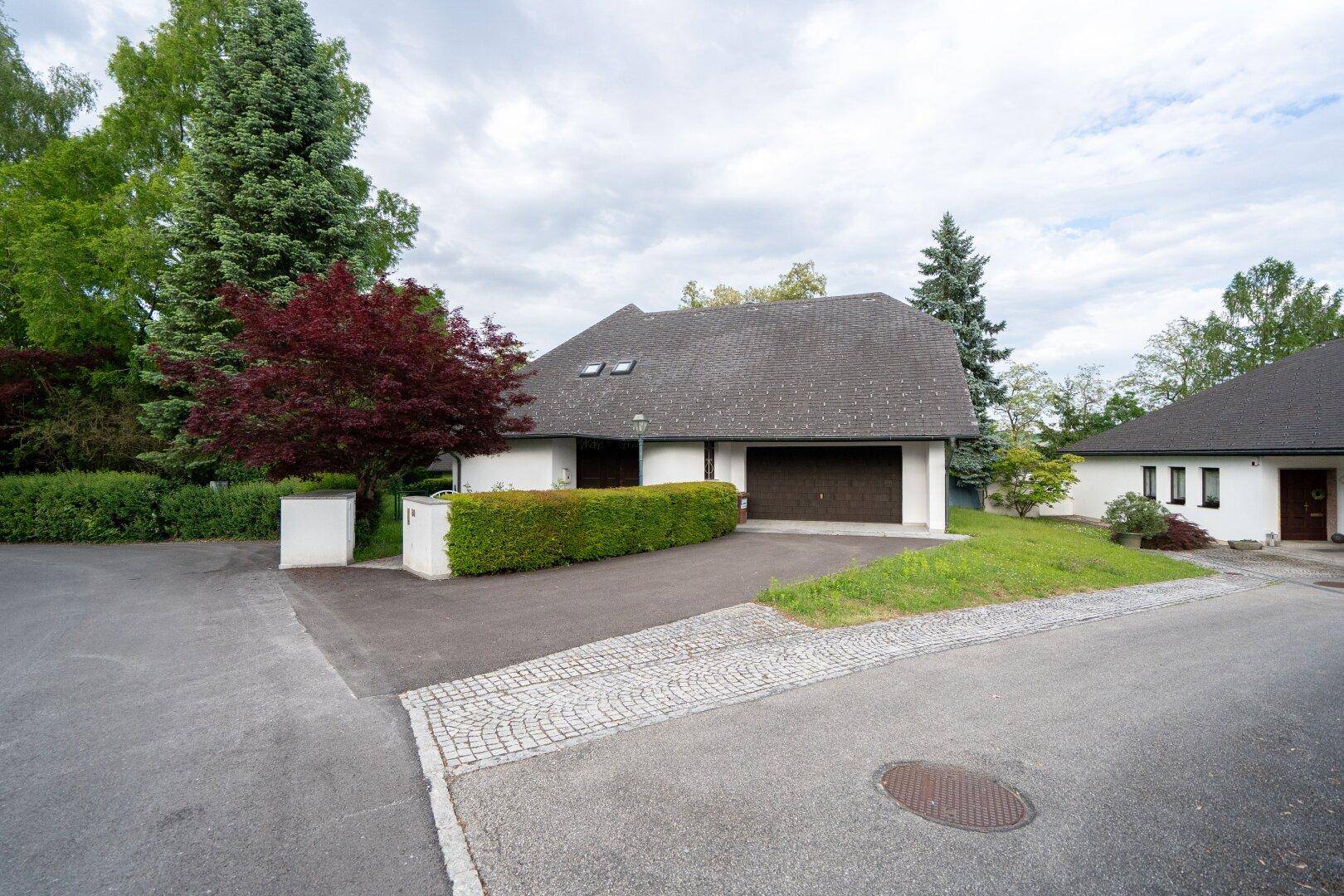 Vorderansicht des Hauses mit Auffahrt, Doppelgarage und gepflegter Hecke.