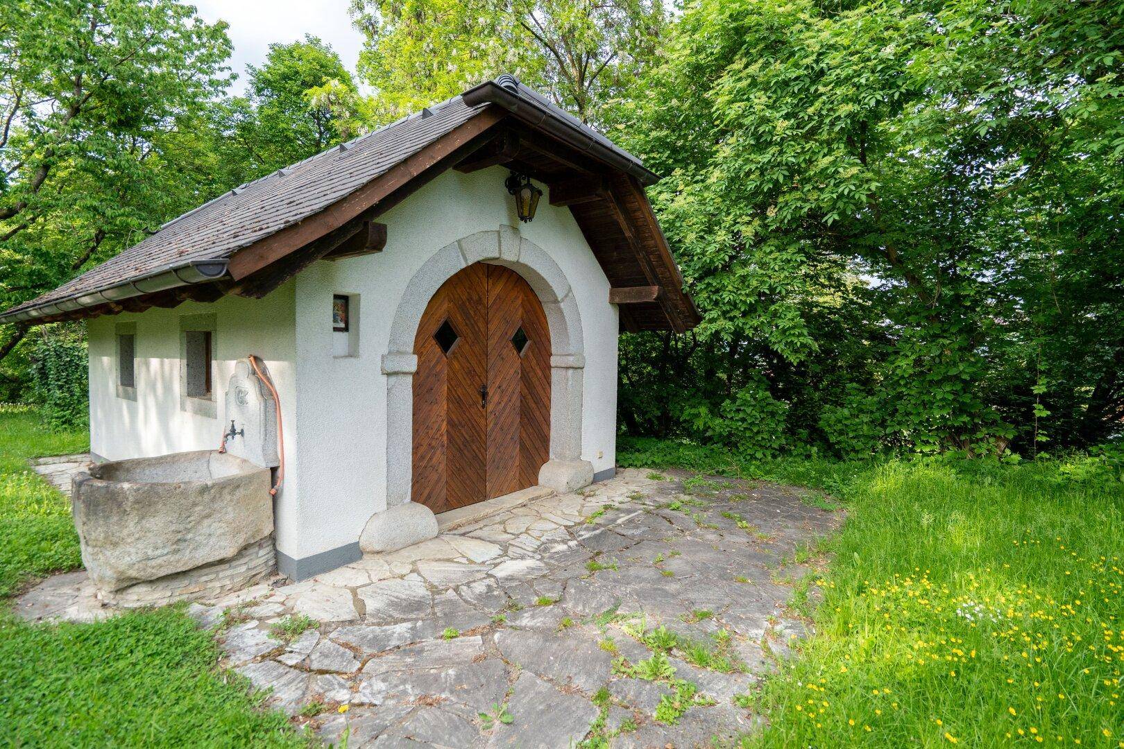 Detailansicht eines charmanten kleinen Gebäudes mit Holztüren und einem Steinbrunnen.