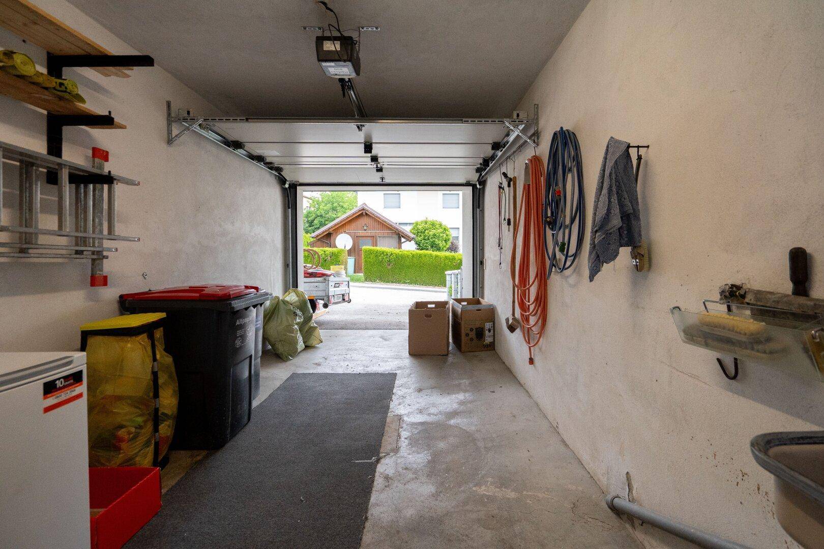 Geräumige Garage mit Betonboden, Stauraum und Blick auf die Einfahrt.