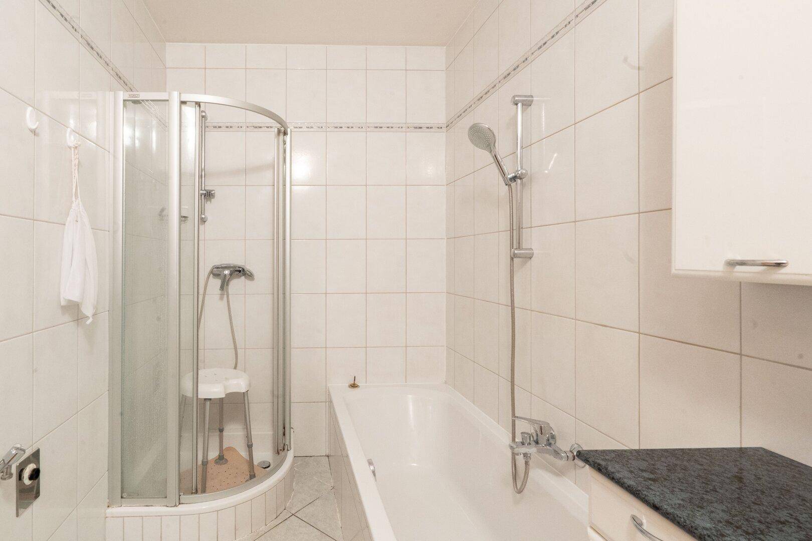 Gefliestes Badezimmer mit Badewanne, Duschkabine und Waschbeckenunterschrank.