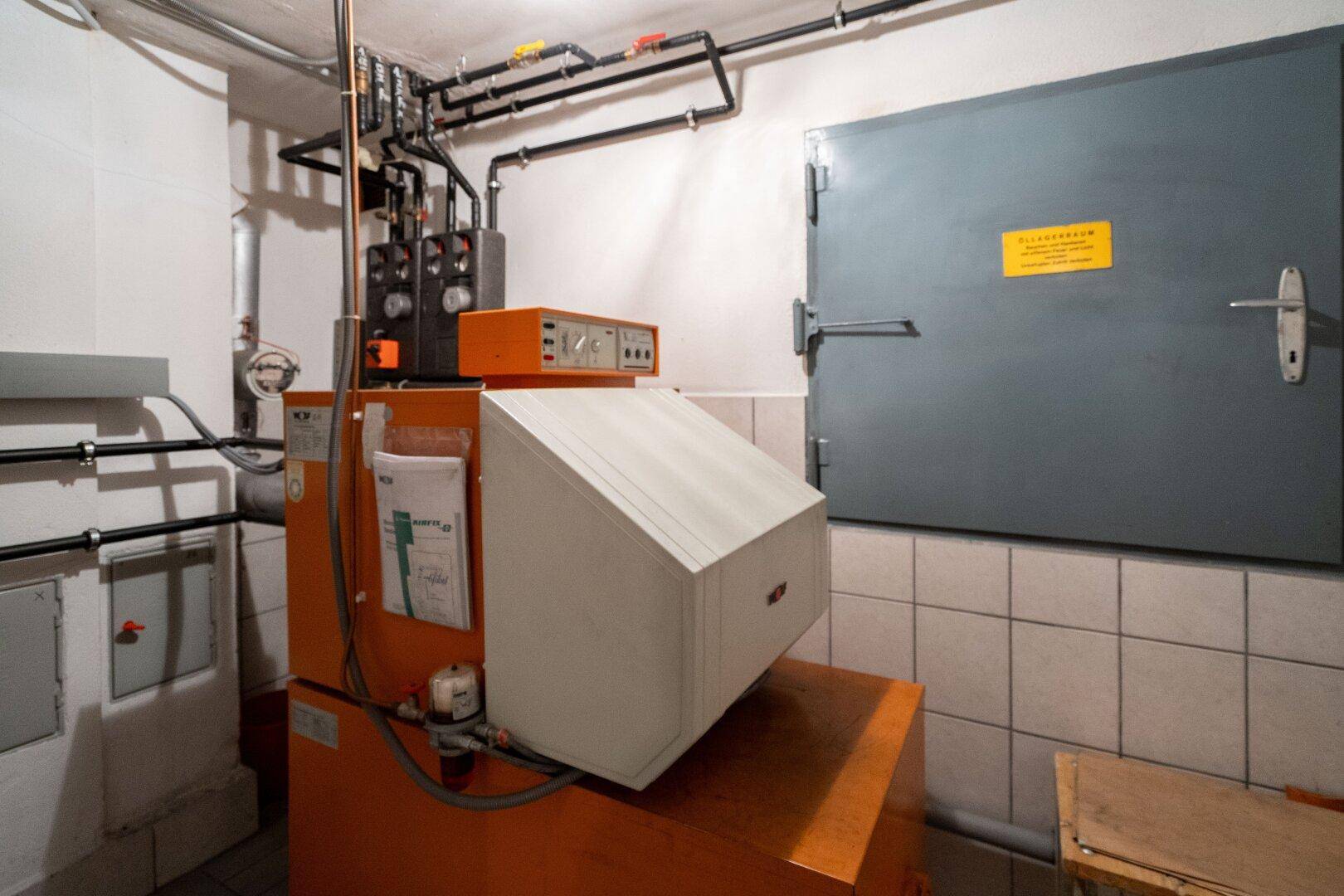 Heizungsraum im Keller mit Kesselanlage, Rohrleitungen und gefliesten Wänden.