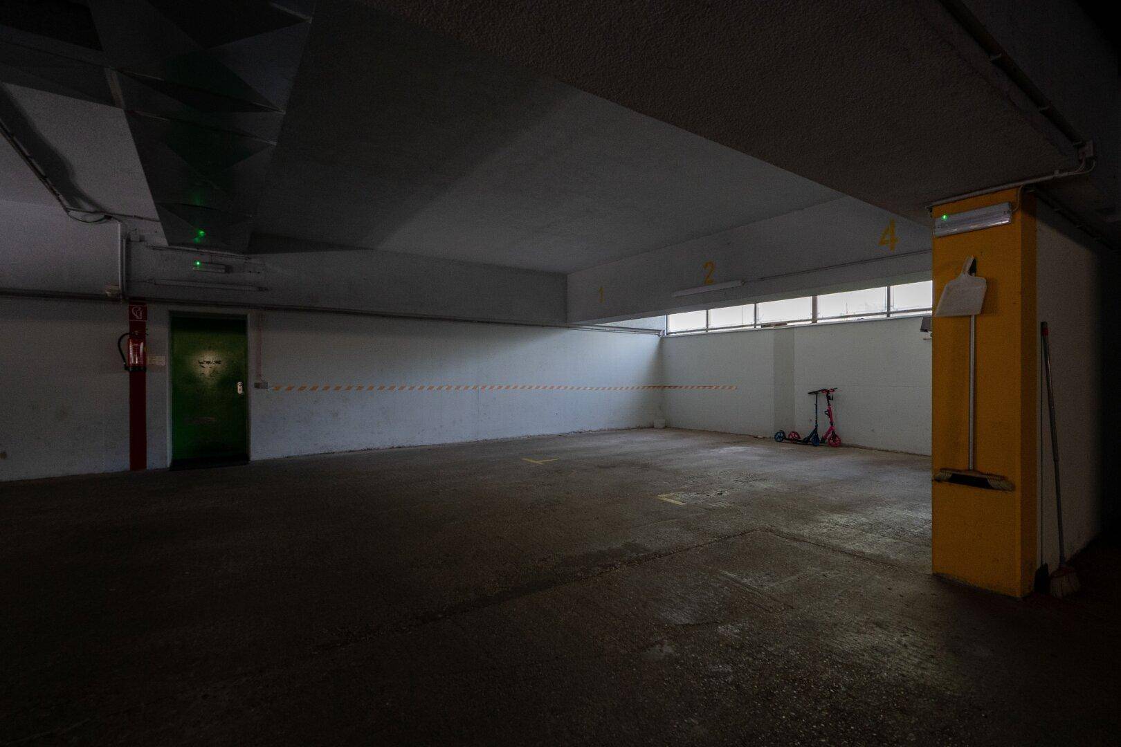 Geräumige Tiefgarage mit Betonboden und natürlichem Lichteinfall durch Fenster.
