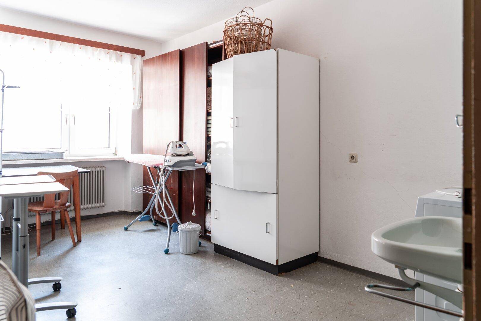 Hauswirtschaftsraum mit Waschbecken, Bügelbrett und Schränken, praktisch für den Haushaltsbedarf.
