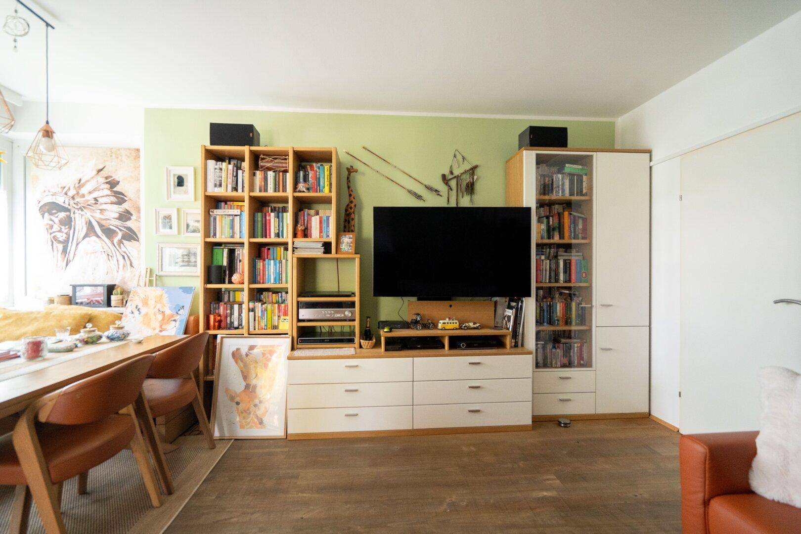Heller Wohn- und Essbereich mit TV-Möbeln, Bücherregalen und einem Esstisch in freundlicher Atmosphäre.