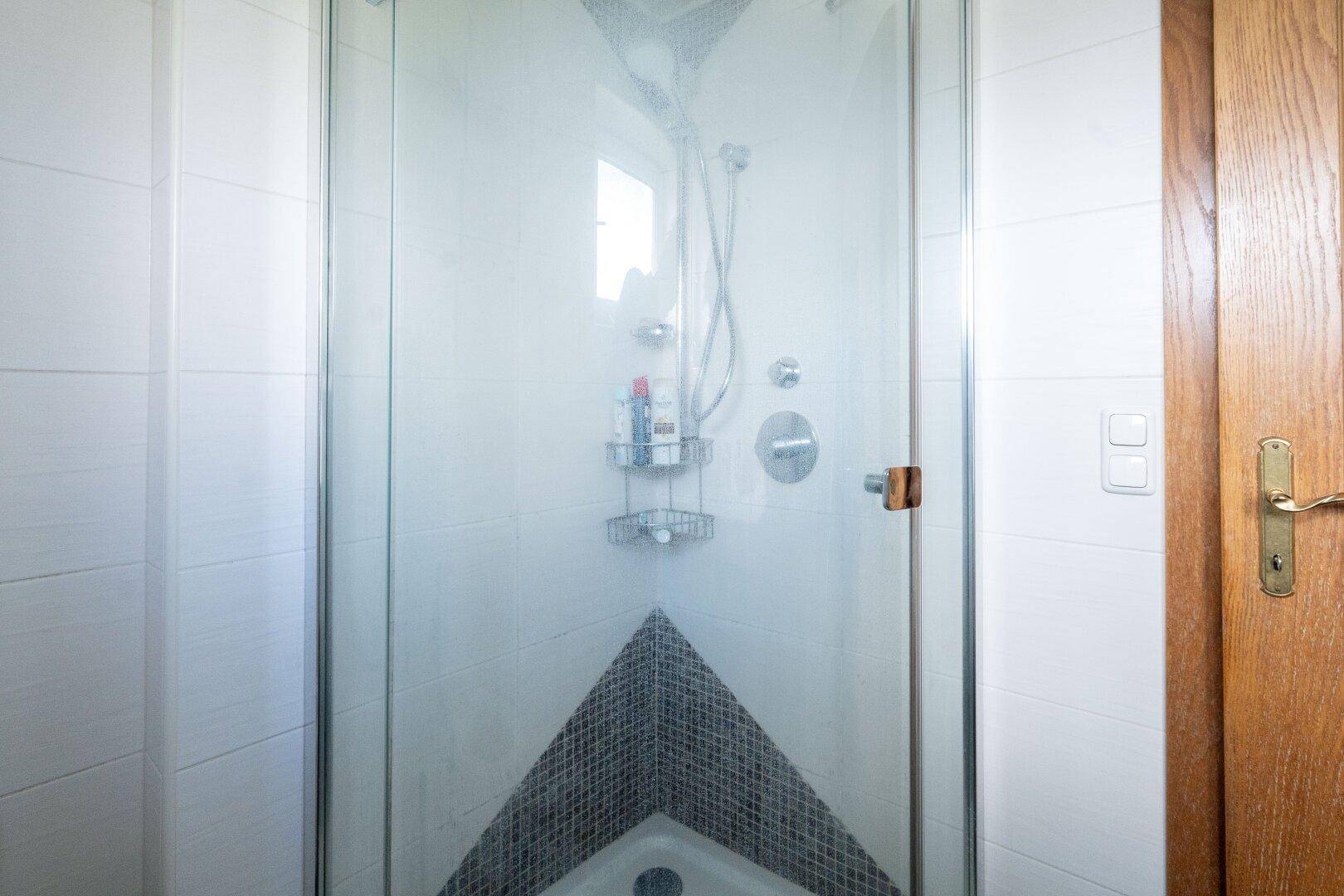 Moderne Duschkabine mit Glaswänden und Fliesen, sauber und funktional.