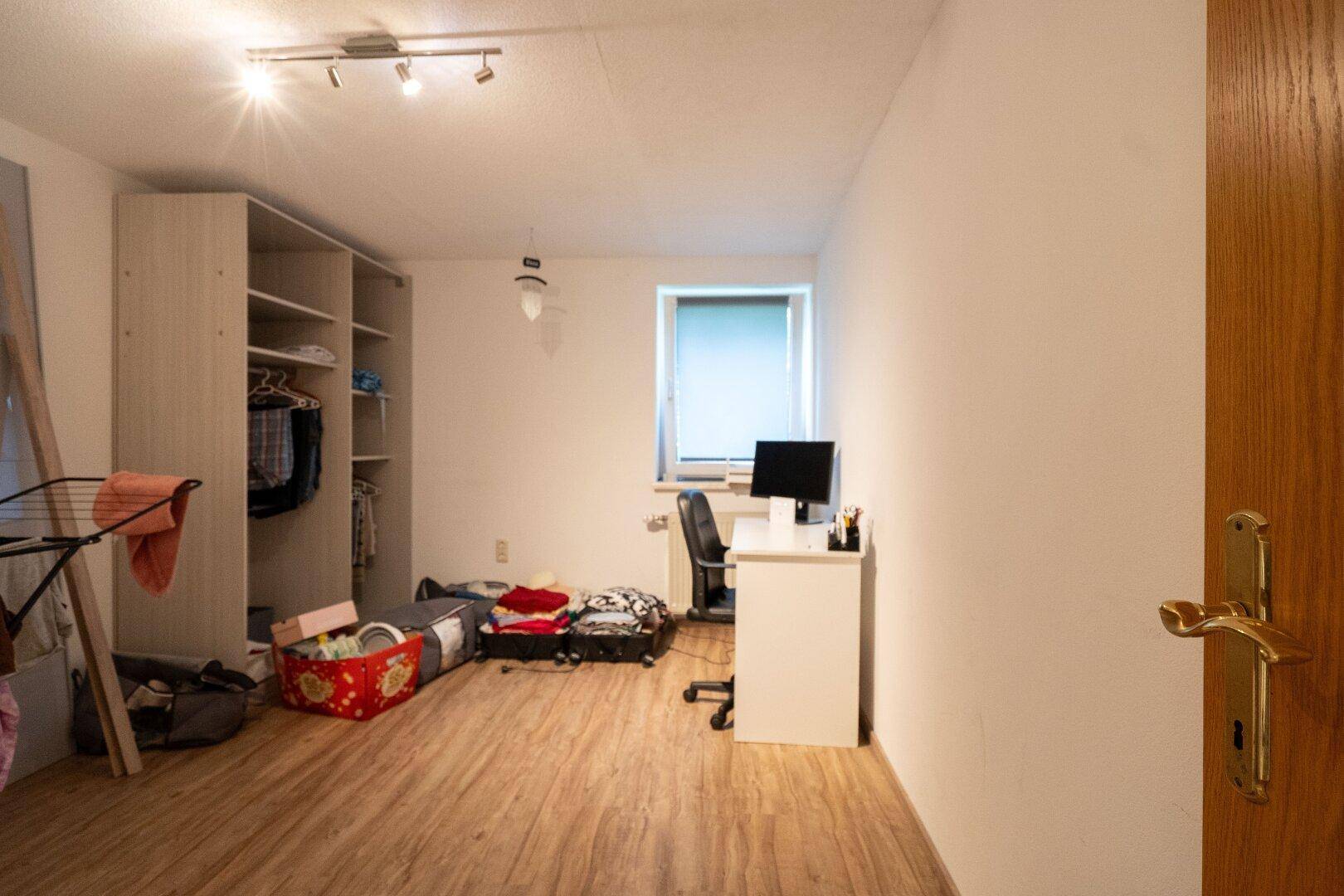 Geräumiges Zimmer mit Schrank, Schreibtisch und Holzboden, vielseitig nutzbar.