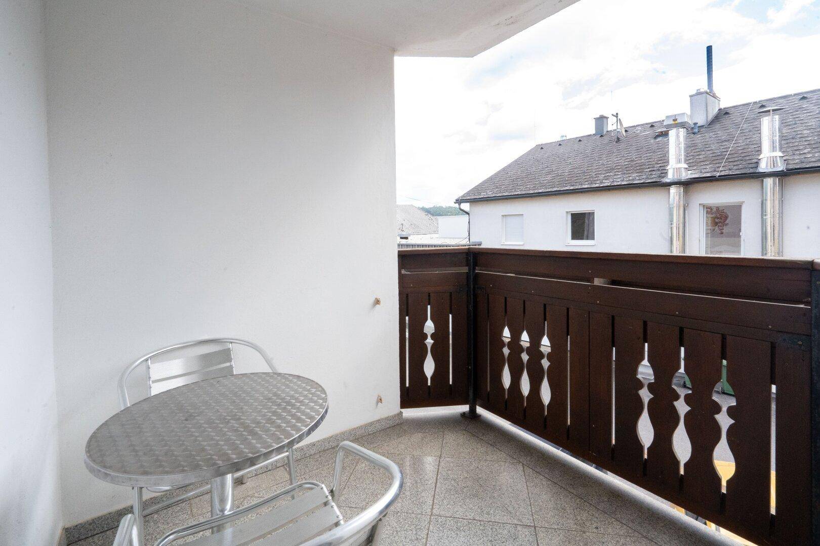Kleiner Balkon mit Metalltisch und Stühlen, ideal für eine Kaffeepause im Freien.