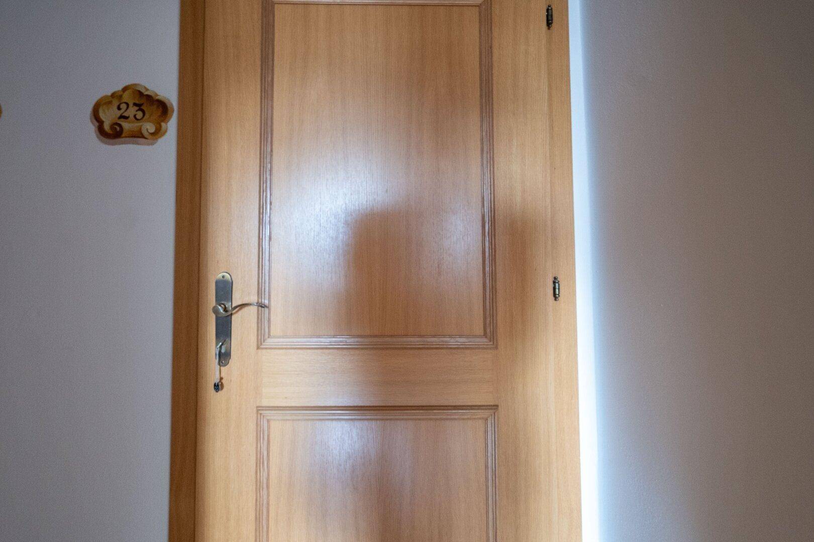 Nahaufnahme einer Holztür mit der Nummer 23, die zu einem Zimmer führt.