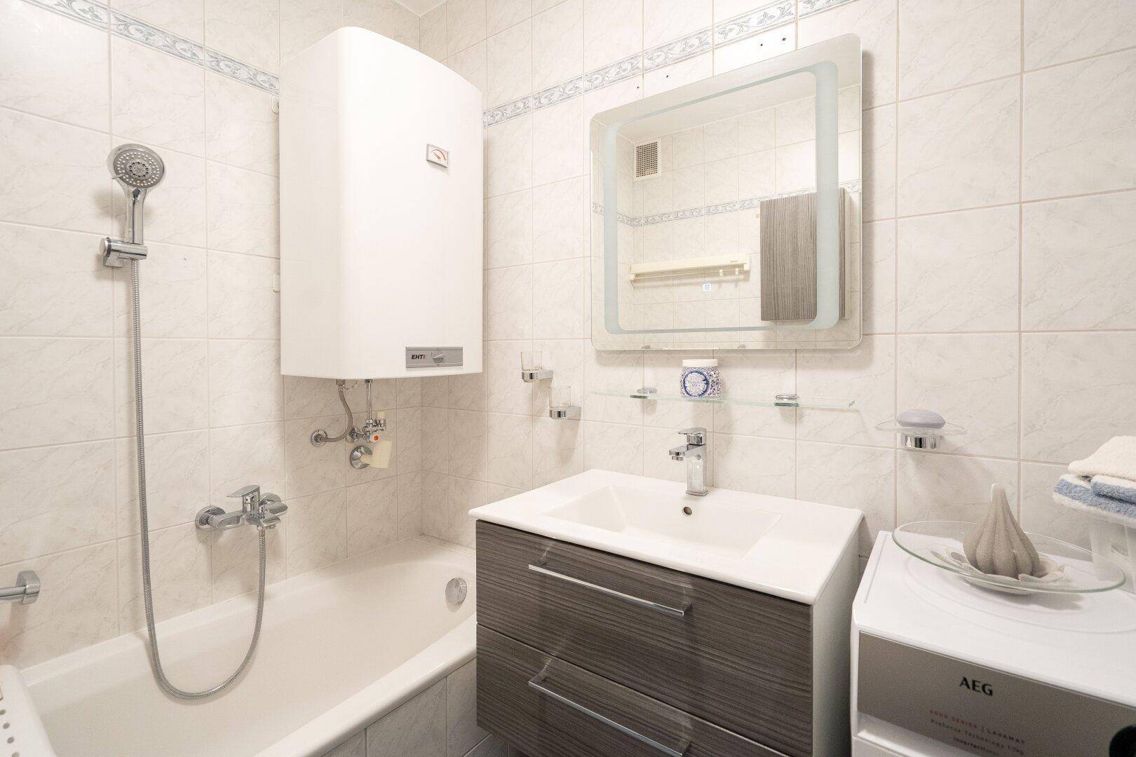 Gefliestes Badezimmer mit Badewanne, Waschbecken und Spiegelschrank.