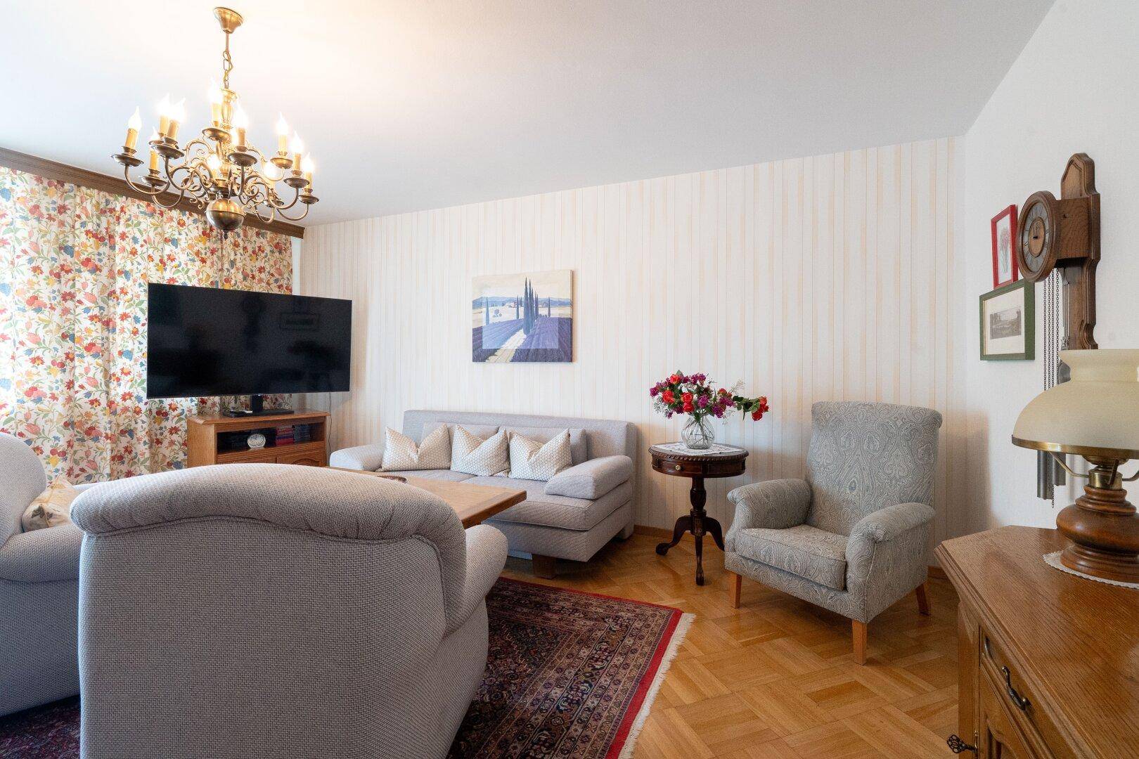 Helles Wohnzimmer mit bequemen Sofas, Fernseher und Blick auf den Garten.