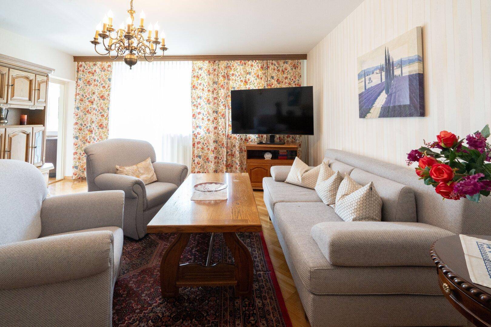 Geräumiges Wohnzimmer mit bequemen Sofas, Fernseher und Kronleuchter.