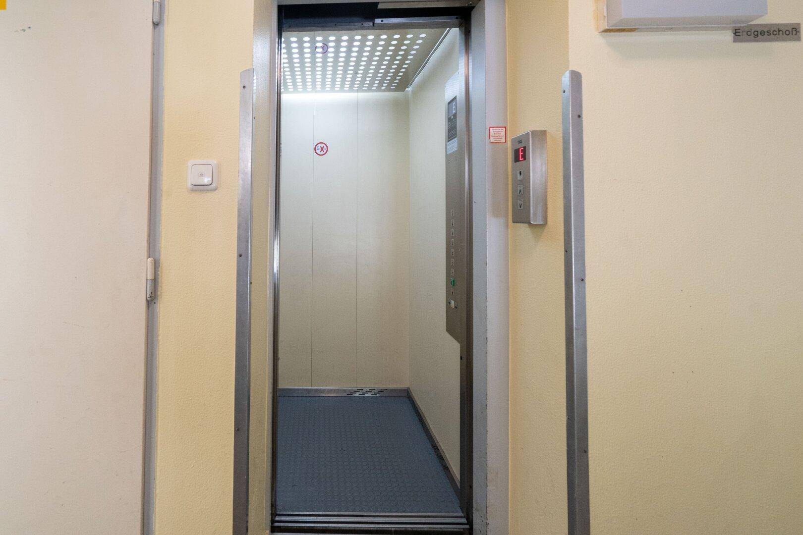 Aufzug im Gebäude mit Metalltüren und Beleuchtung.