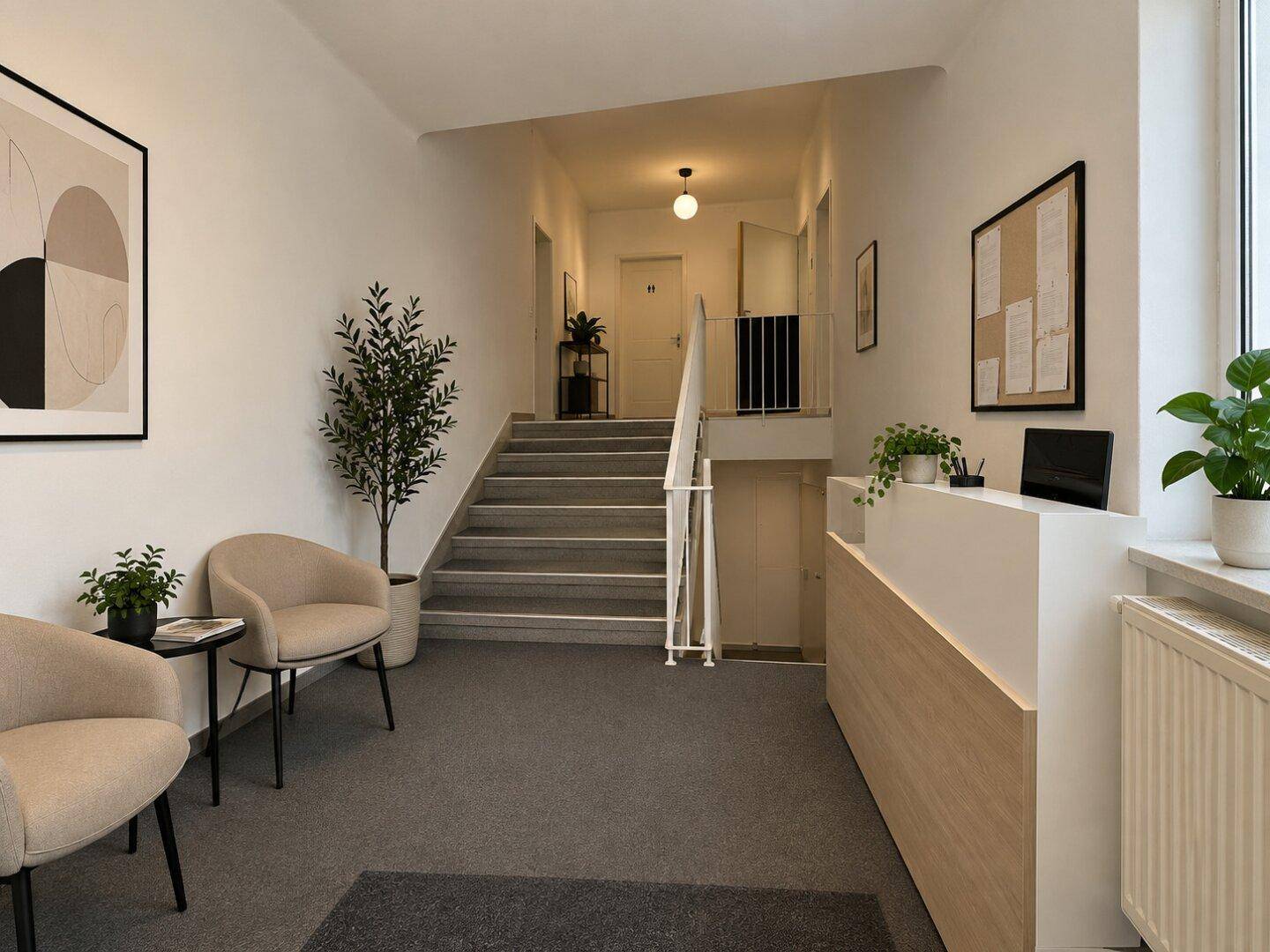 Heller Empfangsbereich mit Treppenaufgang, Teppichboden und modernen Sitzgelegenheiten.