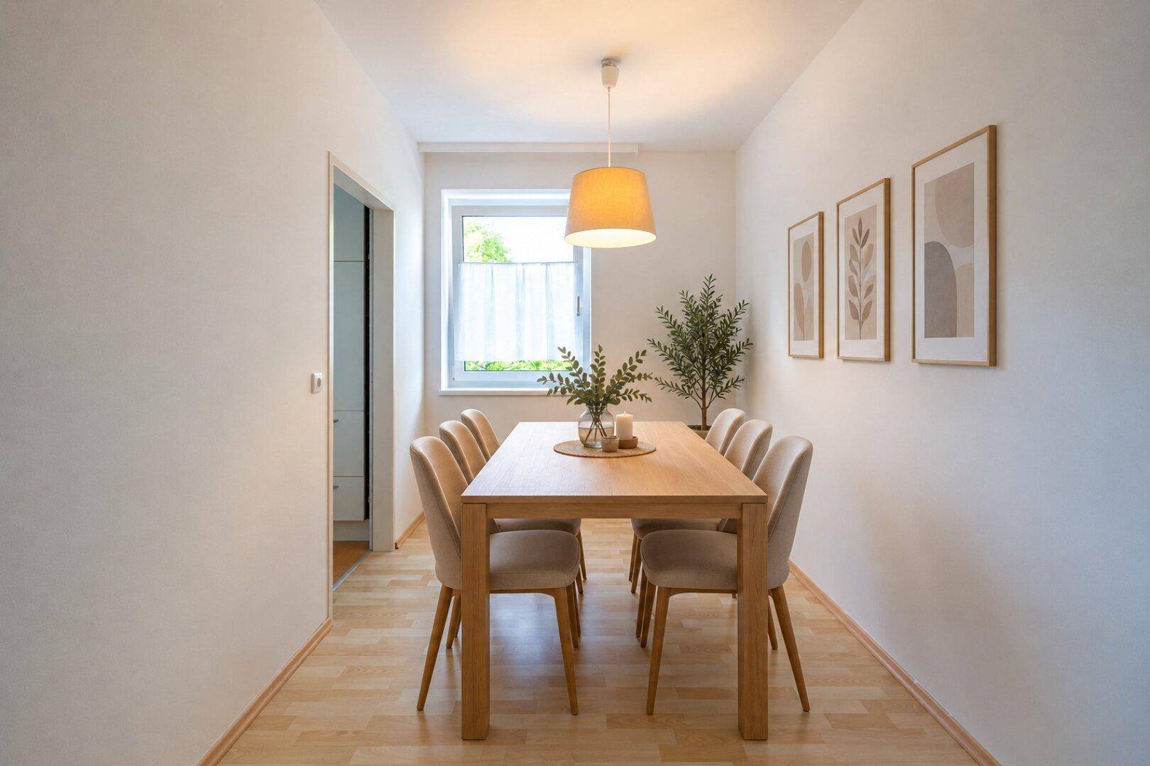 Heller Essbereich mit Holztisch, bequemen Stühlen und dekorativen Bildern an der Wand.