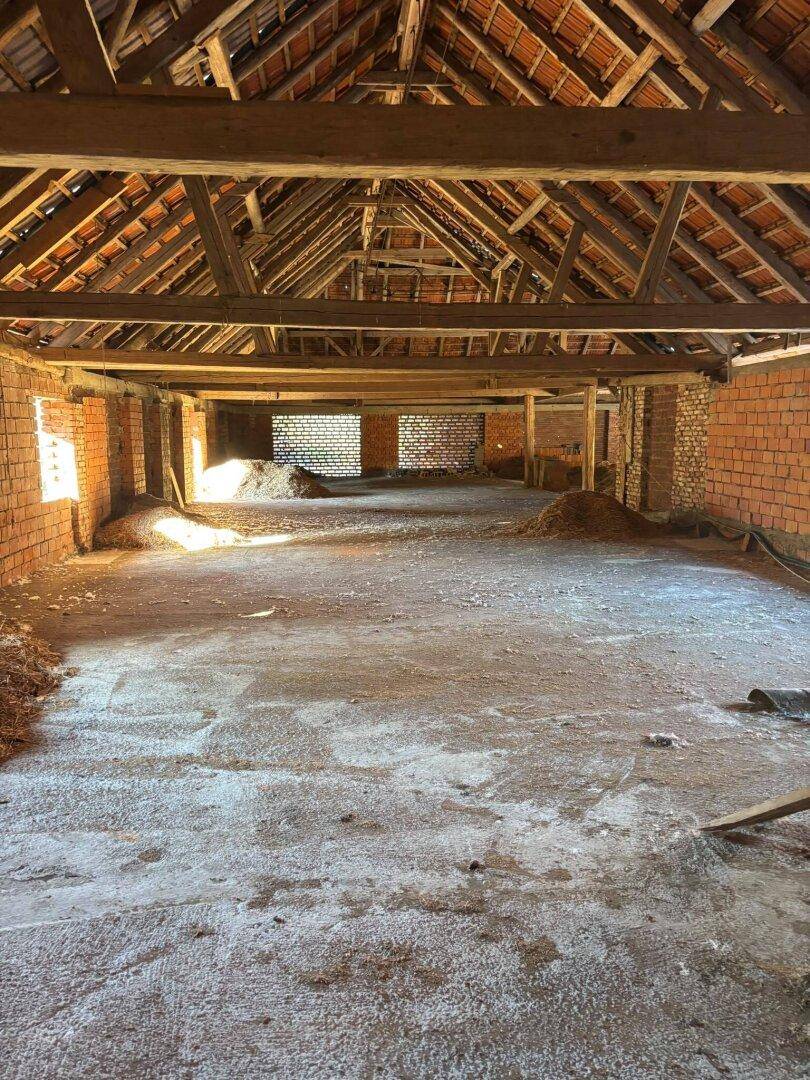 Großer Innenraum mit Holzdachkonstruktion und Ziegelwänden, bietet viel Potenzial für verschiedene Nutzungen.