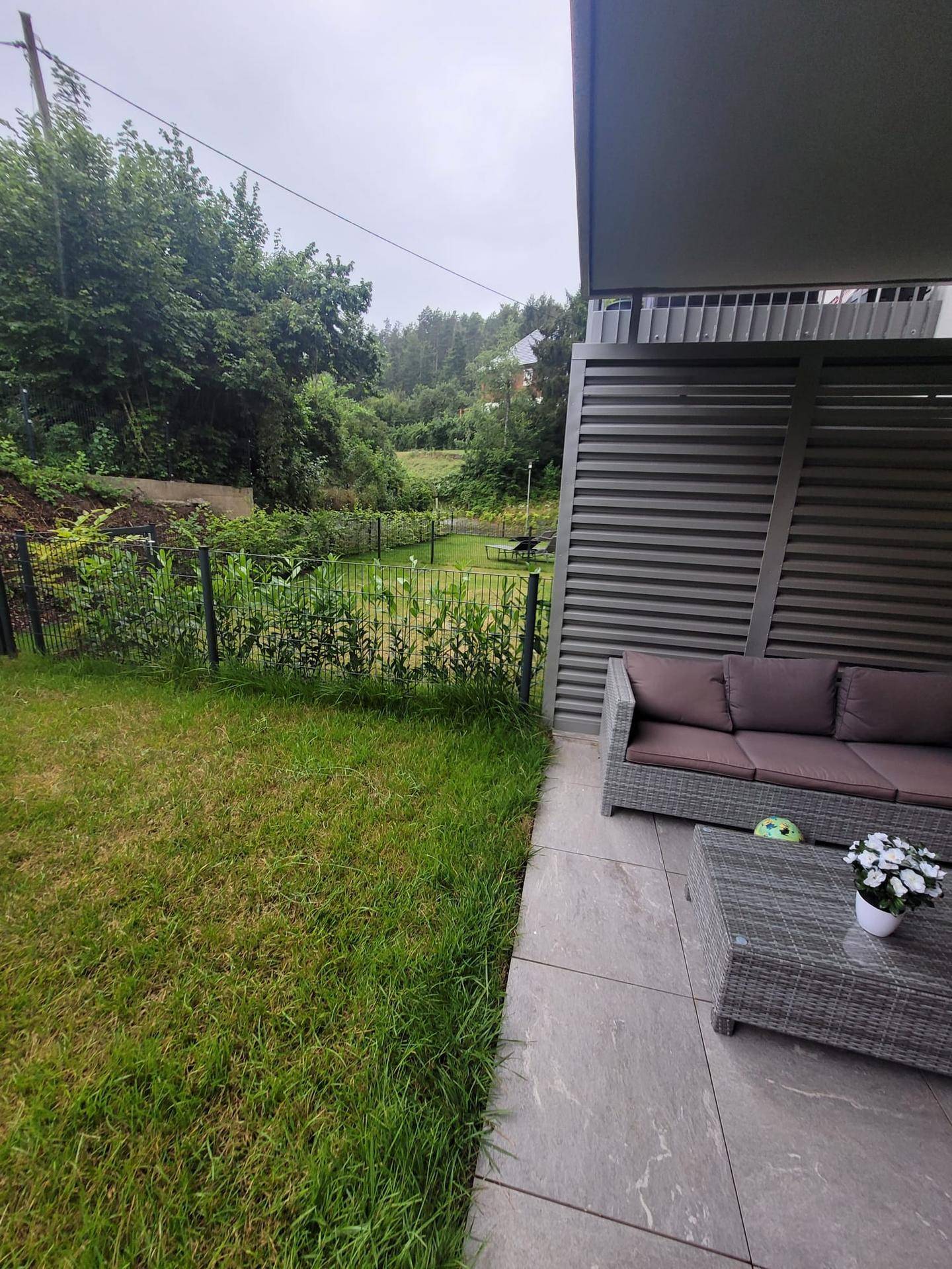 Terrasse mit Blick auf eine grüne, hügelige Landschaft und angrenzendem Gartenbereich.