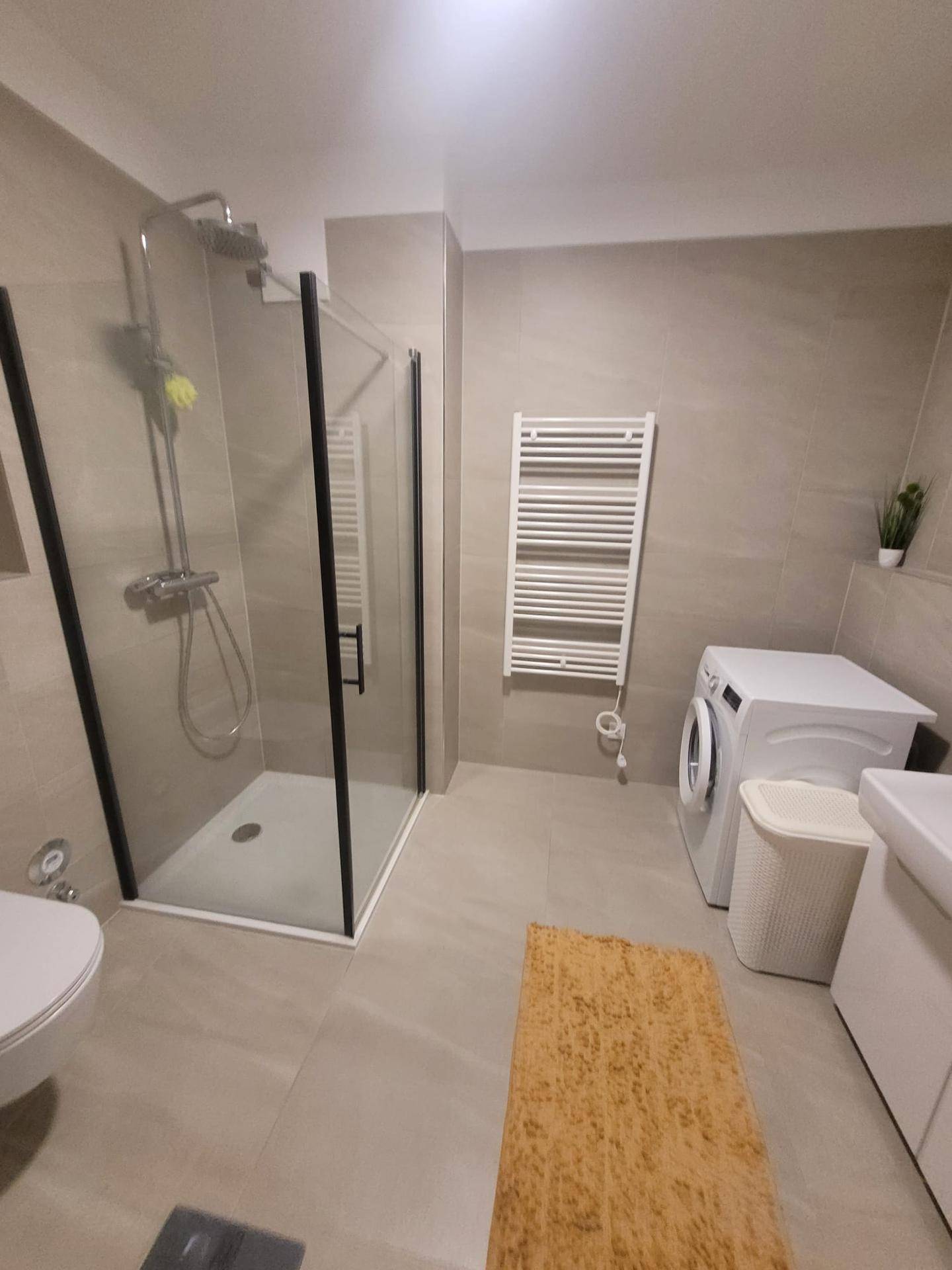 Badezimmer mit begehbarer Dusche, wandhängendem WC und einem praktischen Handtuchheizkörper.