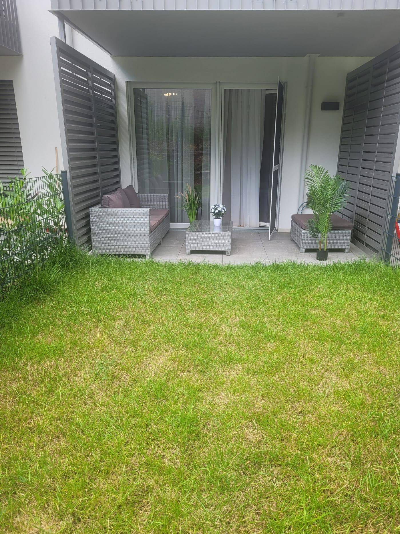Gemütliche Terrasse mit Gartenmöbeln und direktem Zugang zu einem kleinen privaten Rasenbereich.