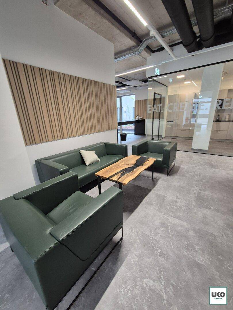 Moderner Büroloungebereich mit grünen Ledersofas, einem einzigartigen Couchtisch und industriellem Design.