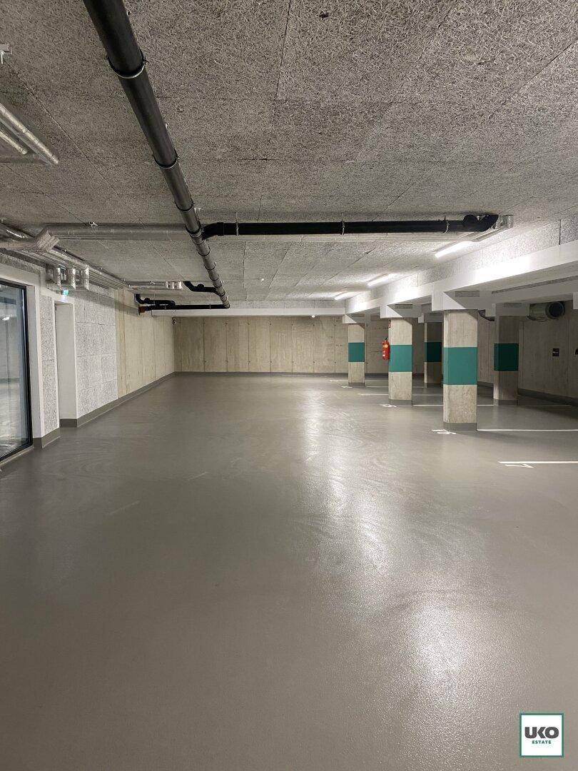 Geräumige Tiefgarage mit Betonboden und klar markierten Parkplätzen, gut beleuchtet.