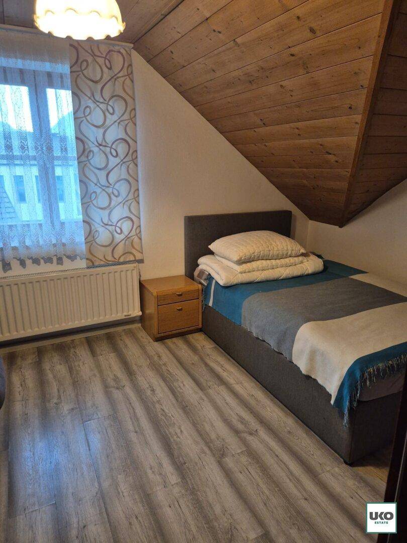 Gemütliches Schlafzimmer im Dachgeschoss mit Holzdachschräge und Laminatboden.
