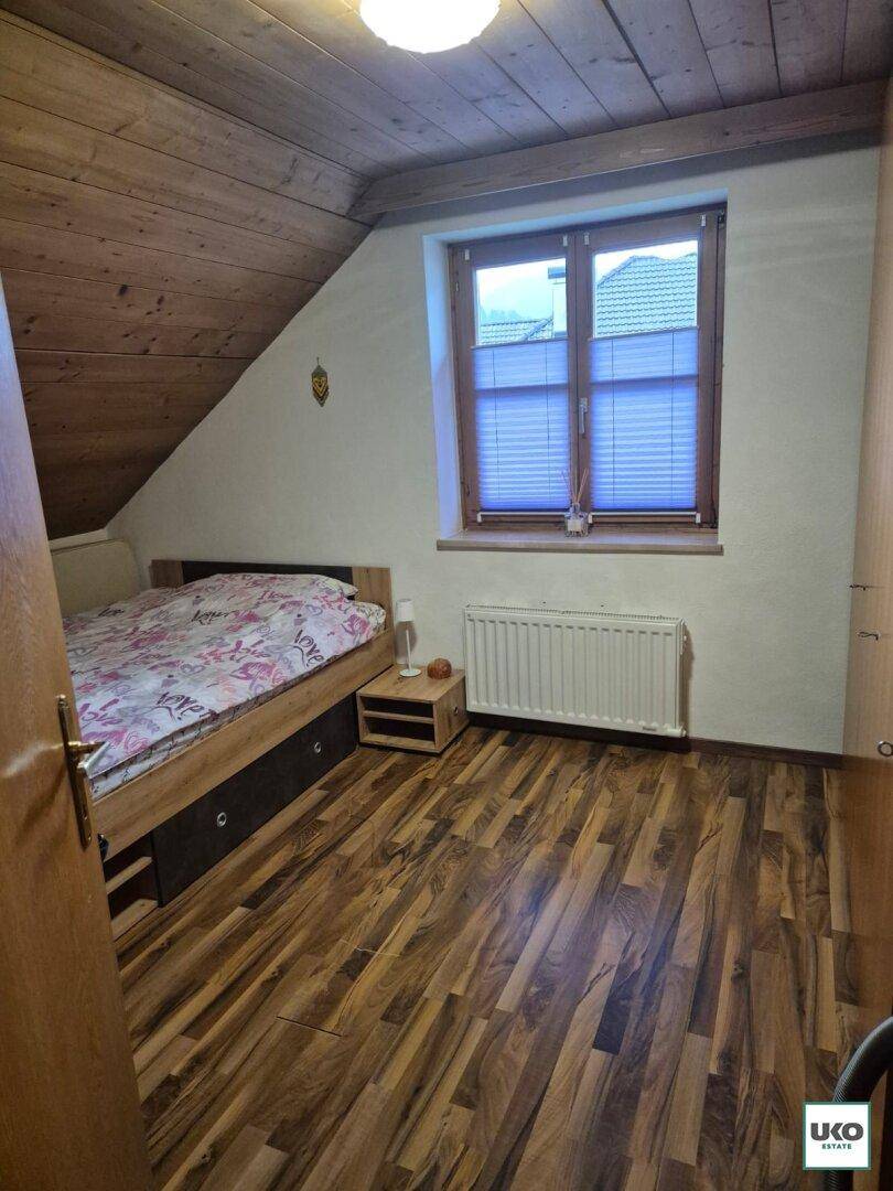 Helles Schlafzimmer im Dachgeschoss mit Holzdachschräge und Laminatboden.