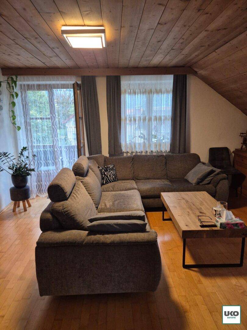 Gemütliches Wohnzimmer mit großem Ecksofa, Holzdeckenverkleidung und Holzboden.