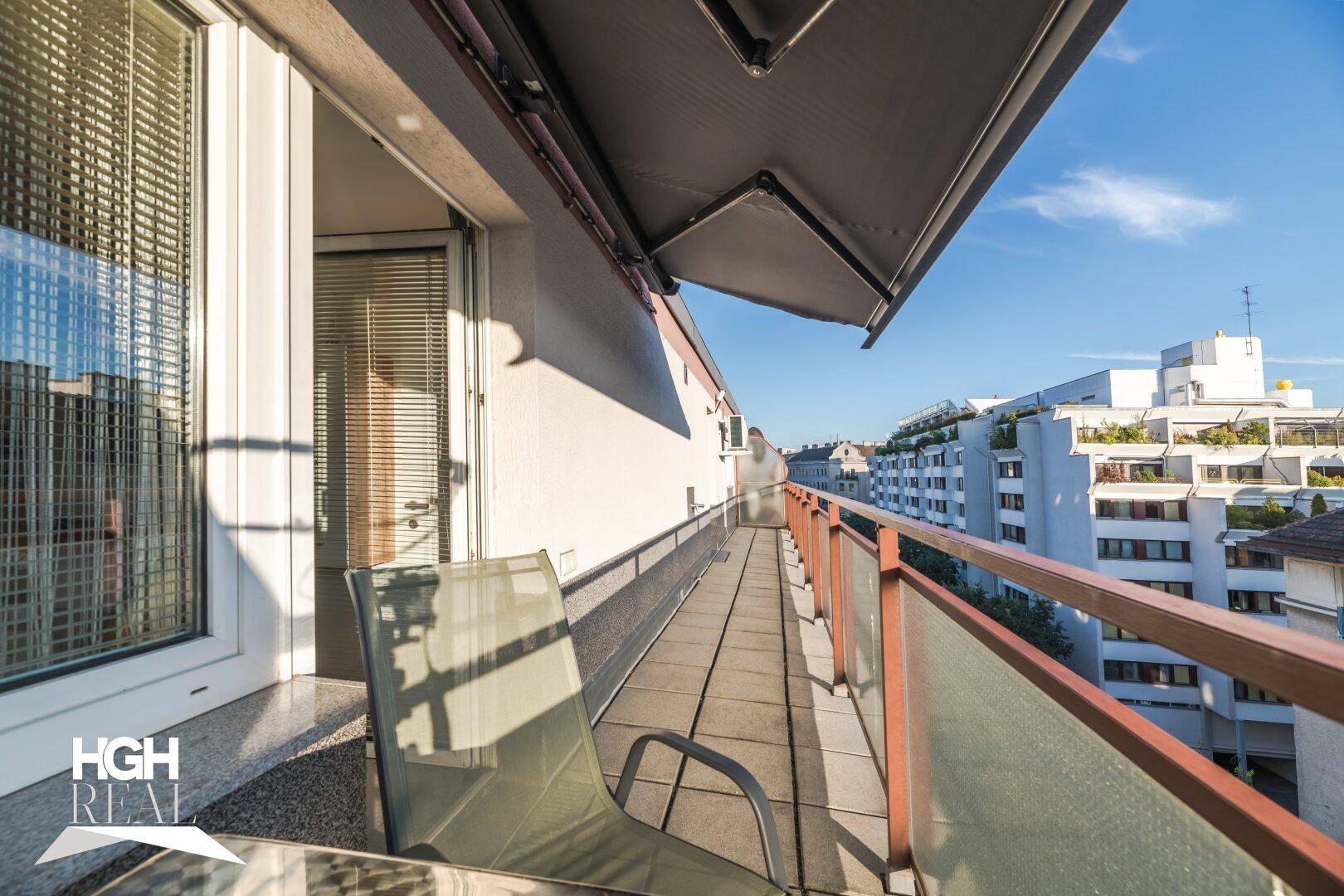 Sonnenverwöhnter Balkon mit Markise, Sitzgelegenheiten und Blick über die Stadt.