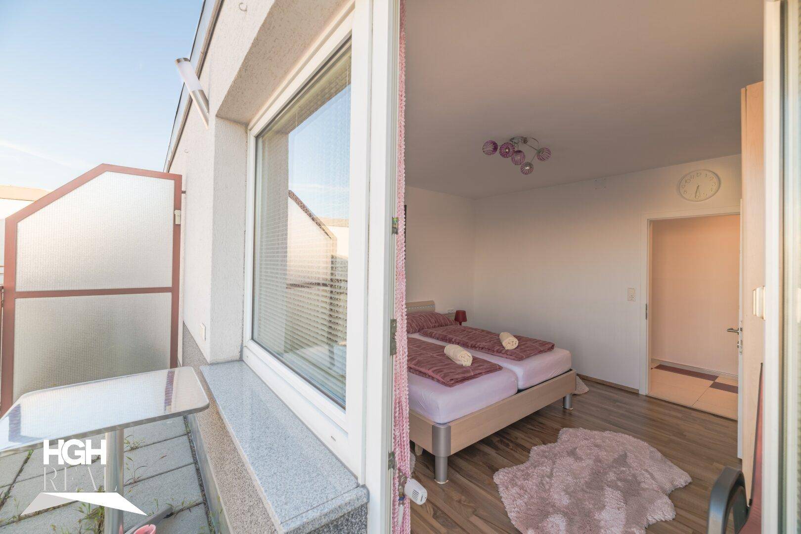Helles Schlafzimmer mit Doppelbett und direktem Zugang zu einem sonnigen Balkon.