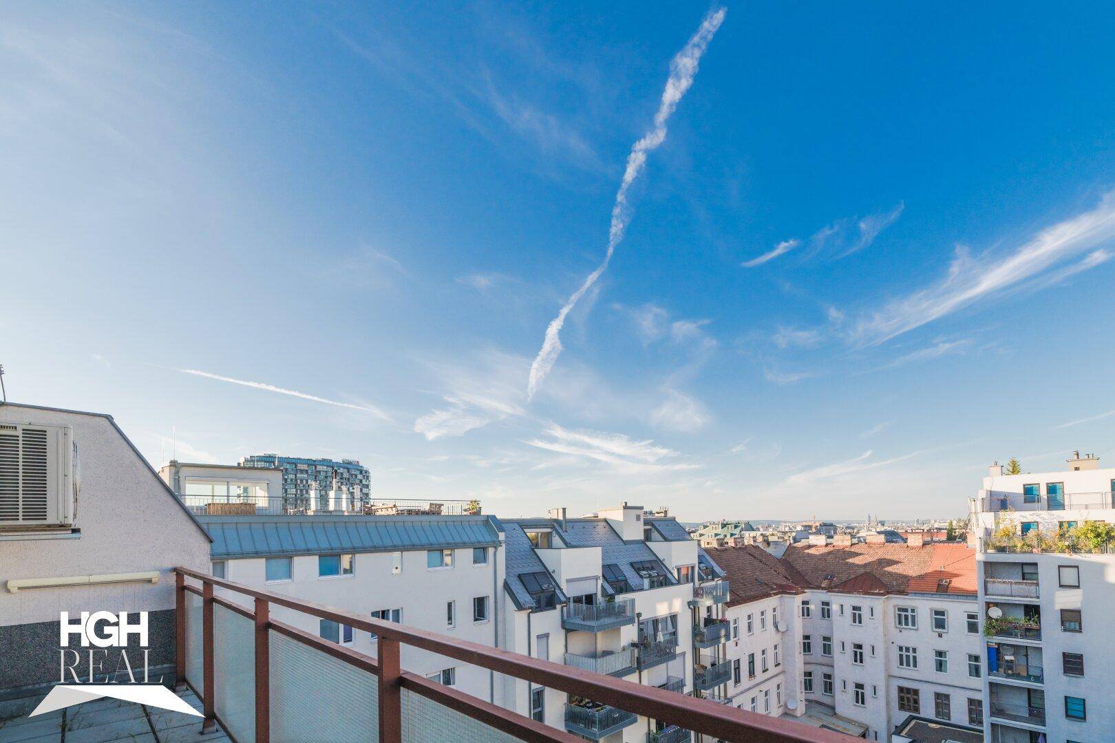 Panoramablick über die Stadt von einem sonnigen Balkon mit moderner Glasbrüstung und weitem Horizont.