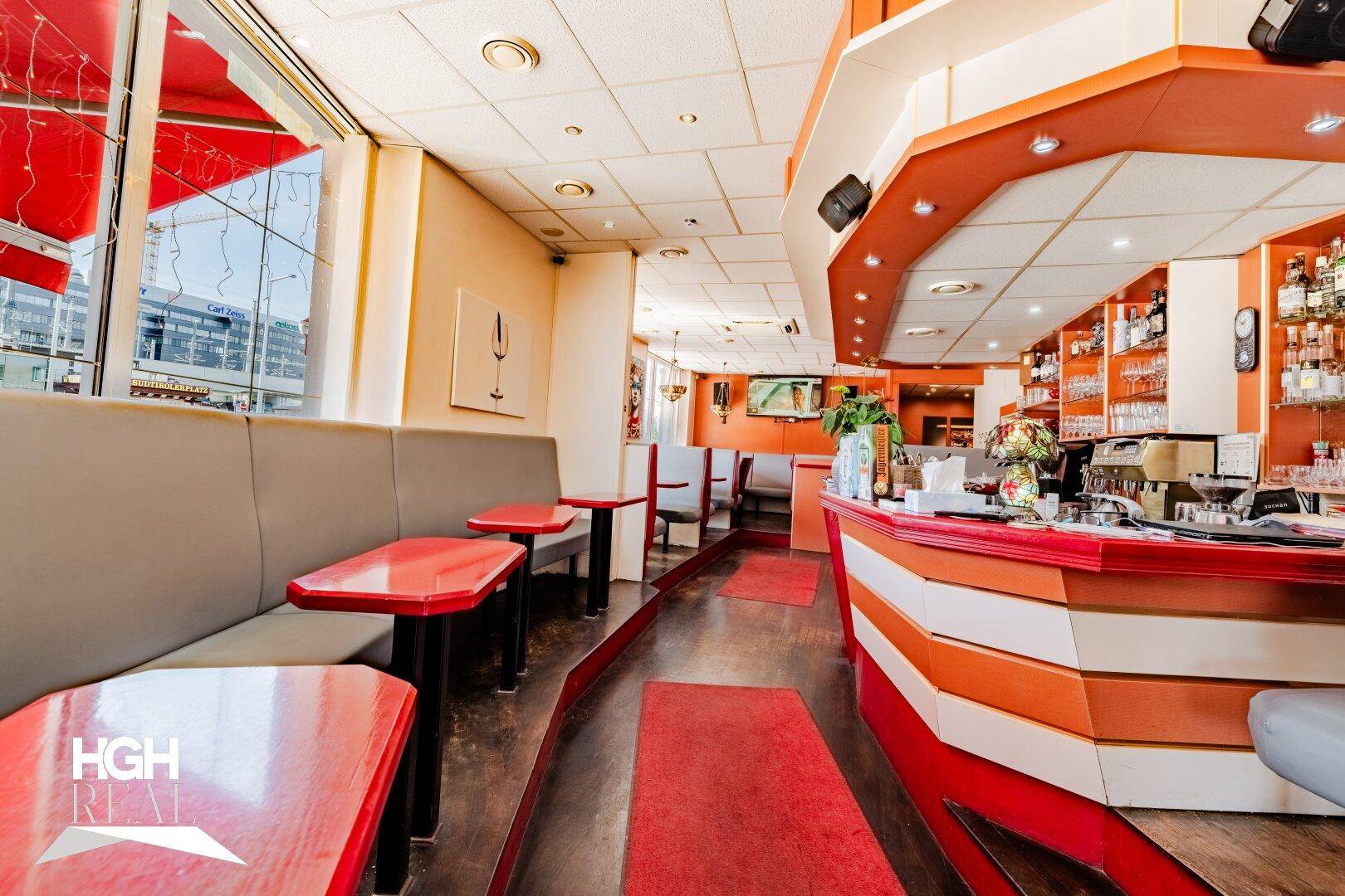Blick auf den Barbereich und weitere Sitzgelegenheiten im Restaurant mit roter und oranger Inneneinrichtung.