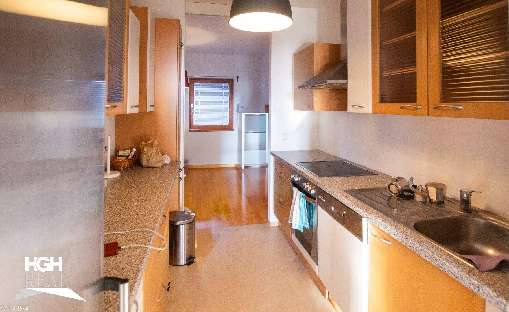 Funktionale Küche mit Einbaugeräten, Spüle und Blick in den angrenzenden Wohnbereich.