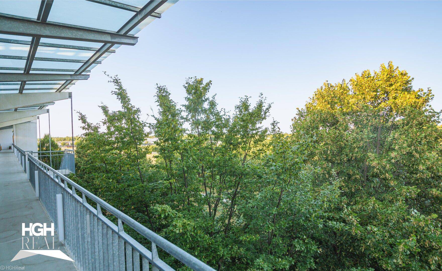 Langer überdachter Balkon mit Metallgeländer und weitem Blick ins Grüne.