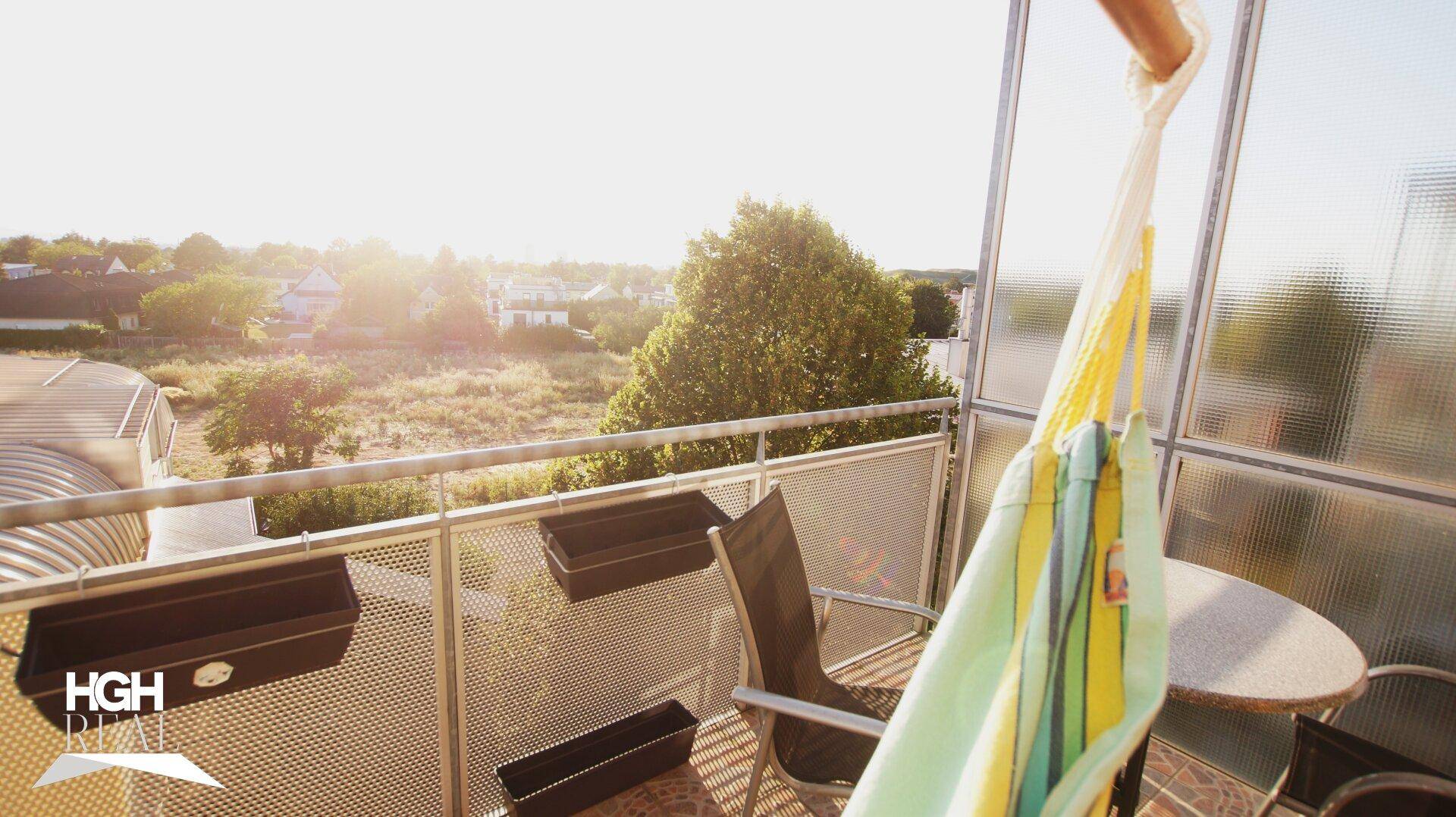 Sonniger Balkon mit Hängematte, Sitzgelegenheiten und weitem Blick ins Grüne.