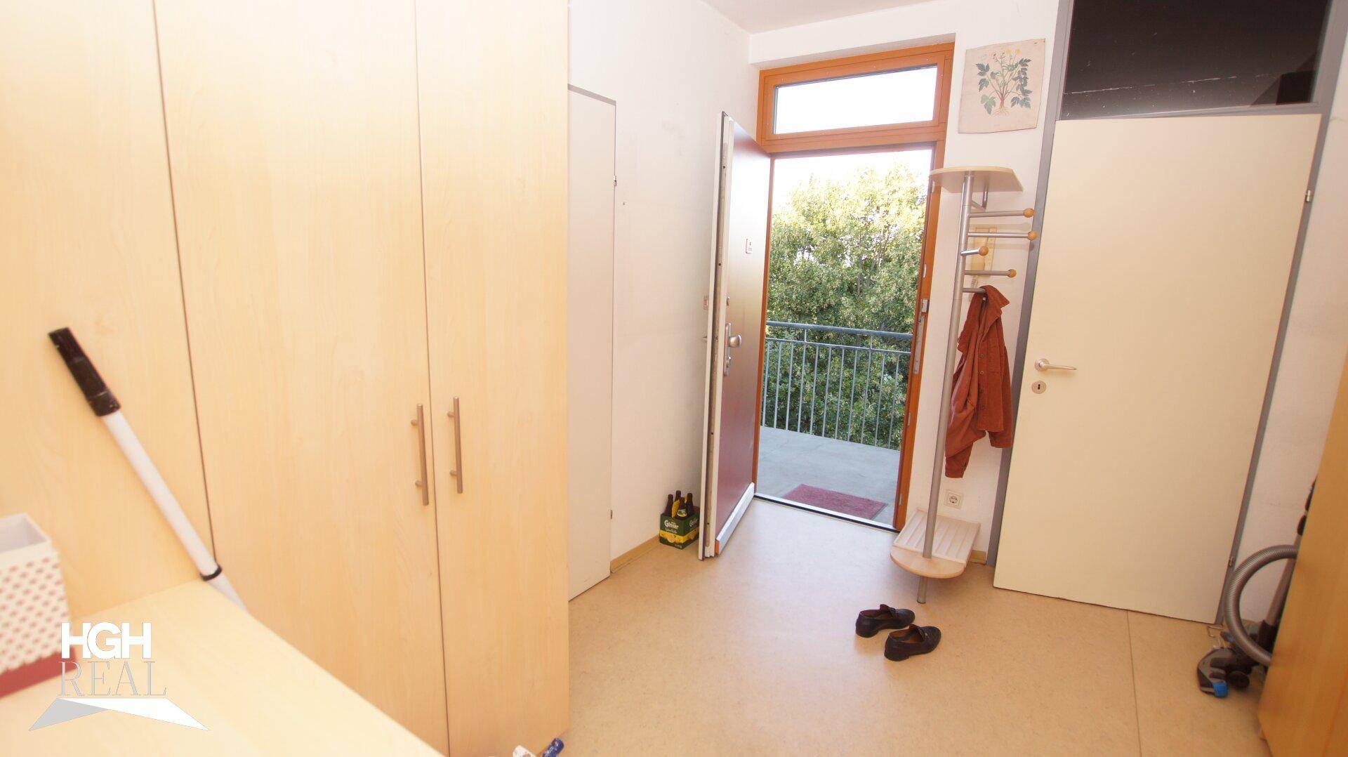Eingangsbereich mit Garderobe und offener Tür zum Balkon mit Blick ins Grüne.