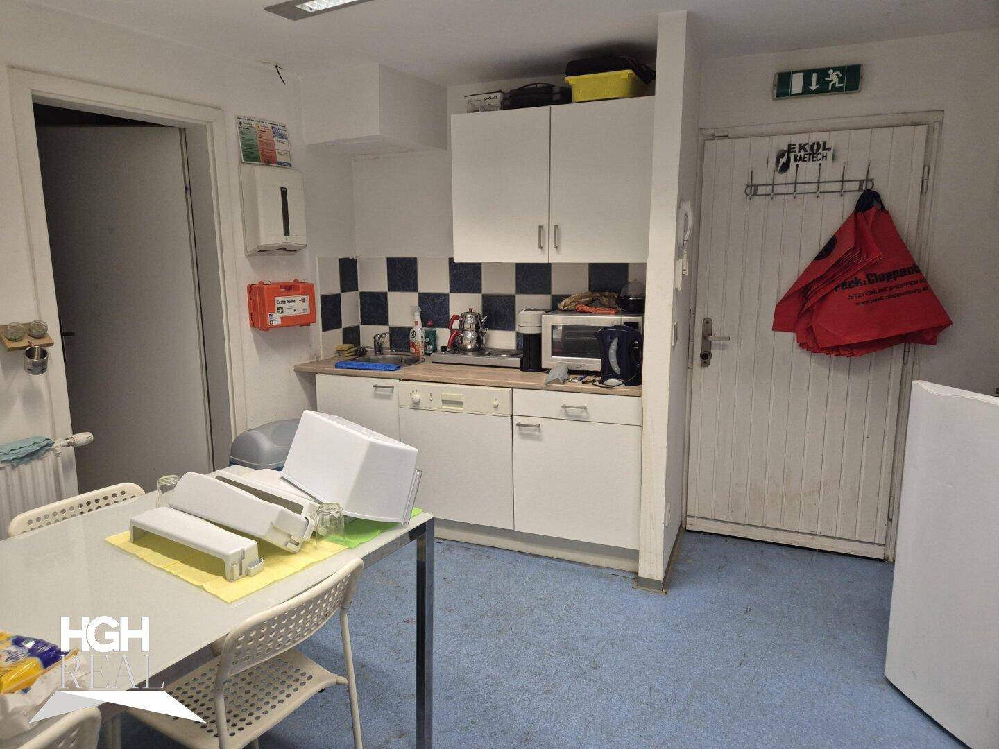 Kleine Küchenzeile mit weißen Schränken, blau-weiß kariertem Fliesenspiegel und Essbereich.