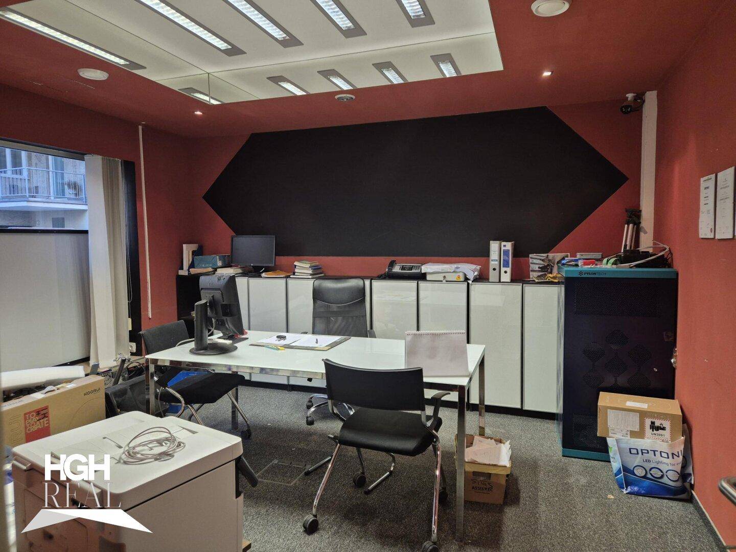 Modernes Büro mit roten Wänden, schwarzer Akzentwand und funktionalen Büromöbeln.