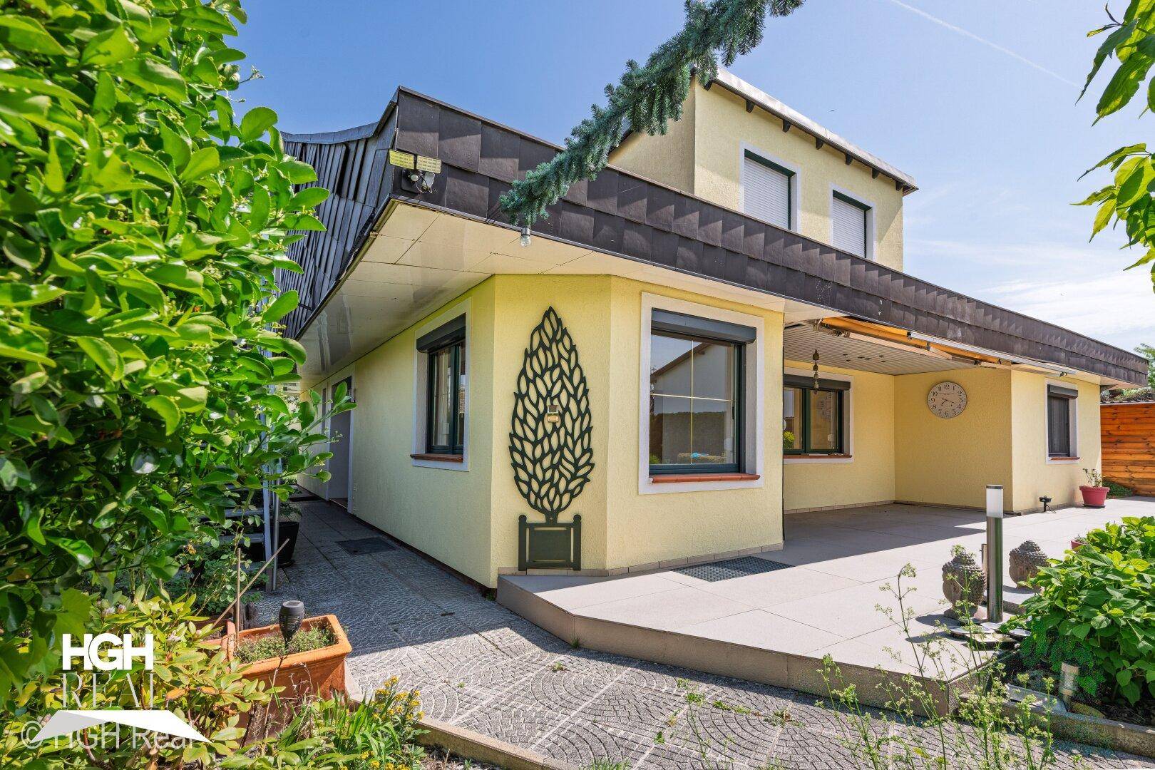 Seitenansicht des Hauses mit Terrasse, Außenbeleuchtung und dekorativem Wandelement.