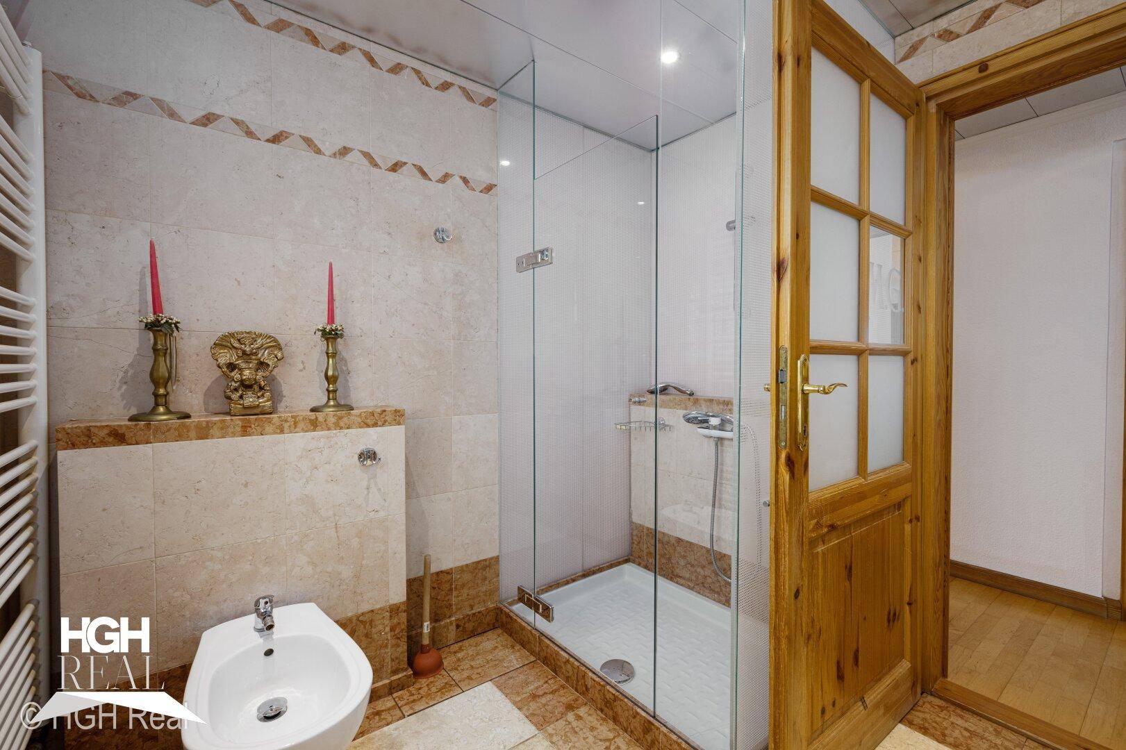 Badezimmer mit Duschkabine, Bidet und gefliesten Wänden in warmen Farbtönen.