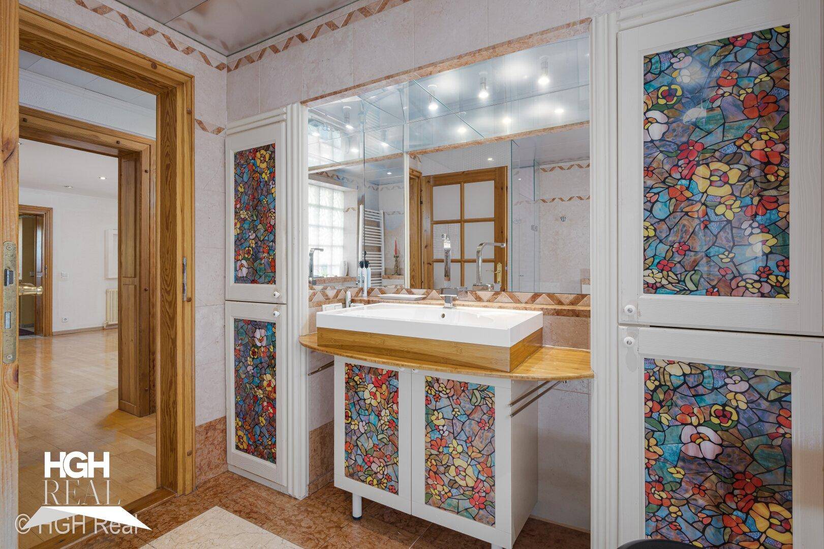Badezimmer mit farbenfrohen Schränken, modernem Aufsatzwaschbecken und Spiegelwand.