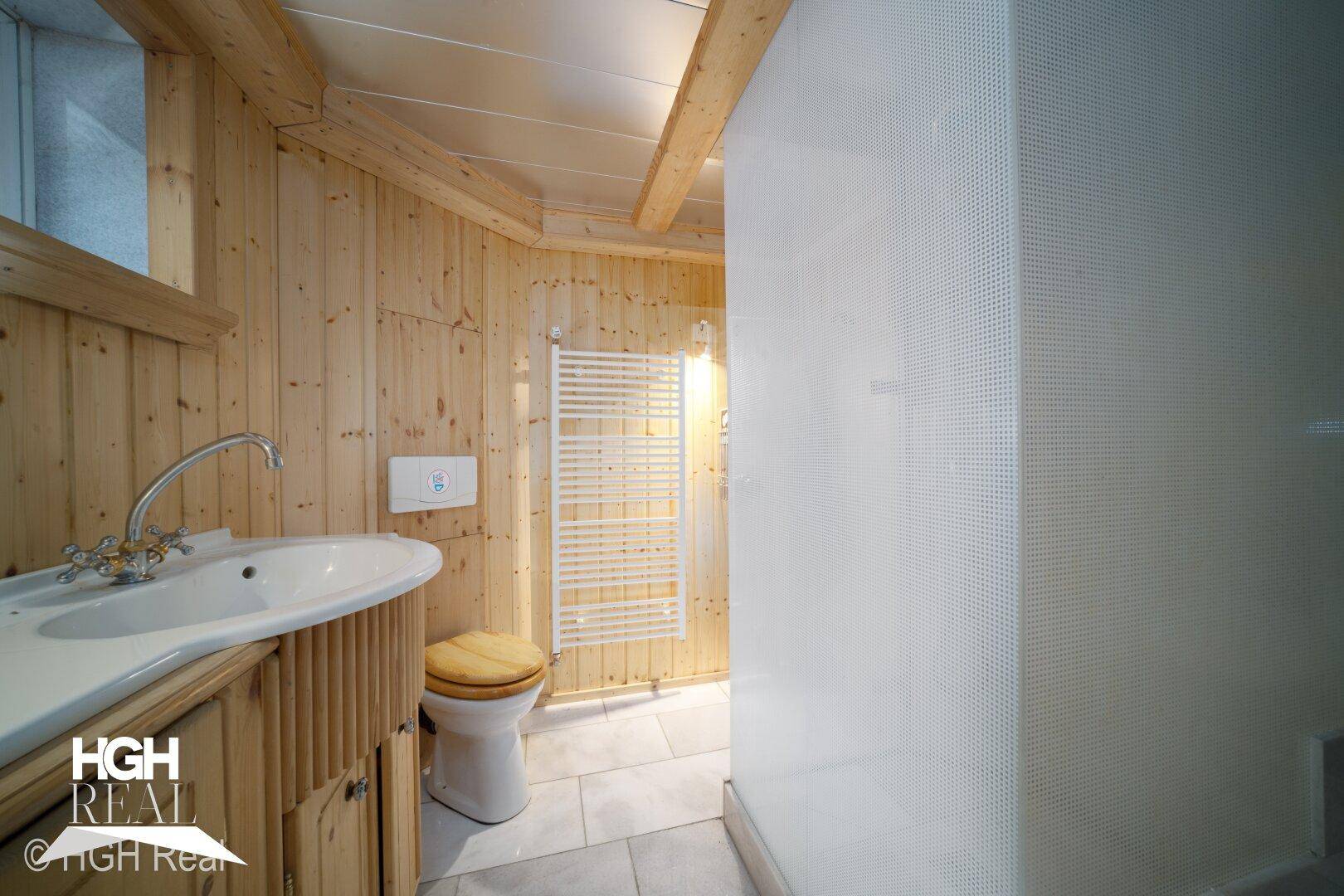 Rustikales Badezimmer mit Holzverkleidung, Dusche und WC.