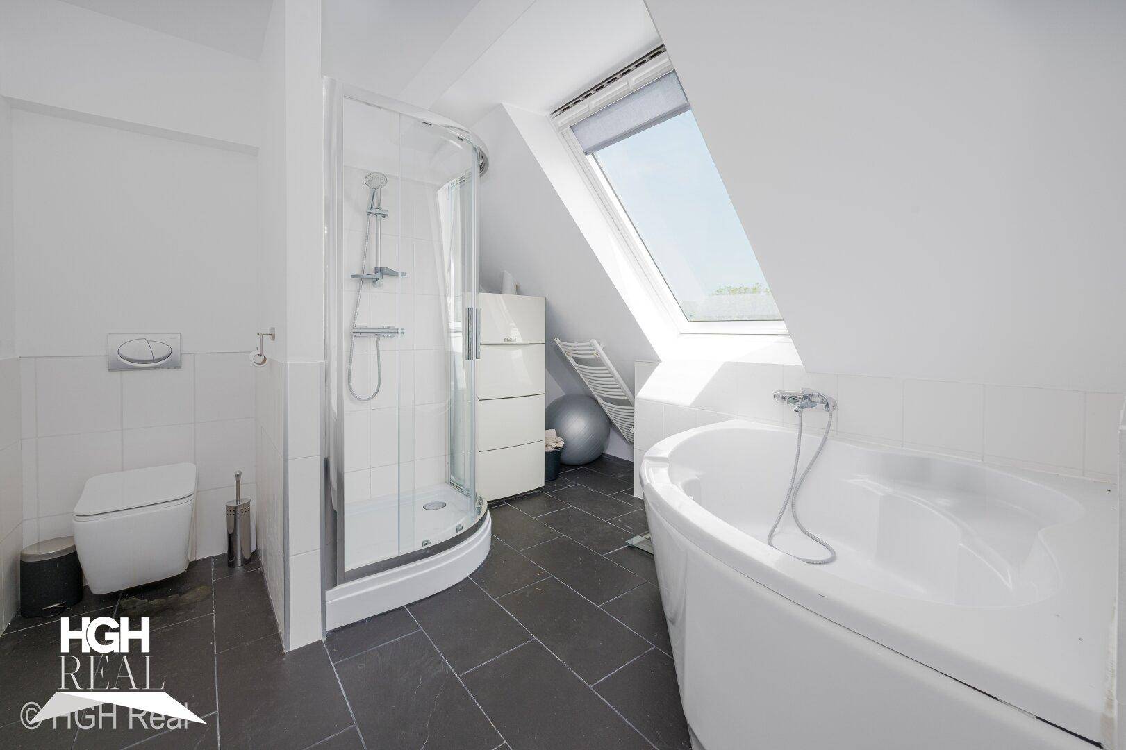 Modernes Dachgeschossbad mit Dusche, Badewanne und dunklen Fliesen.
