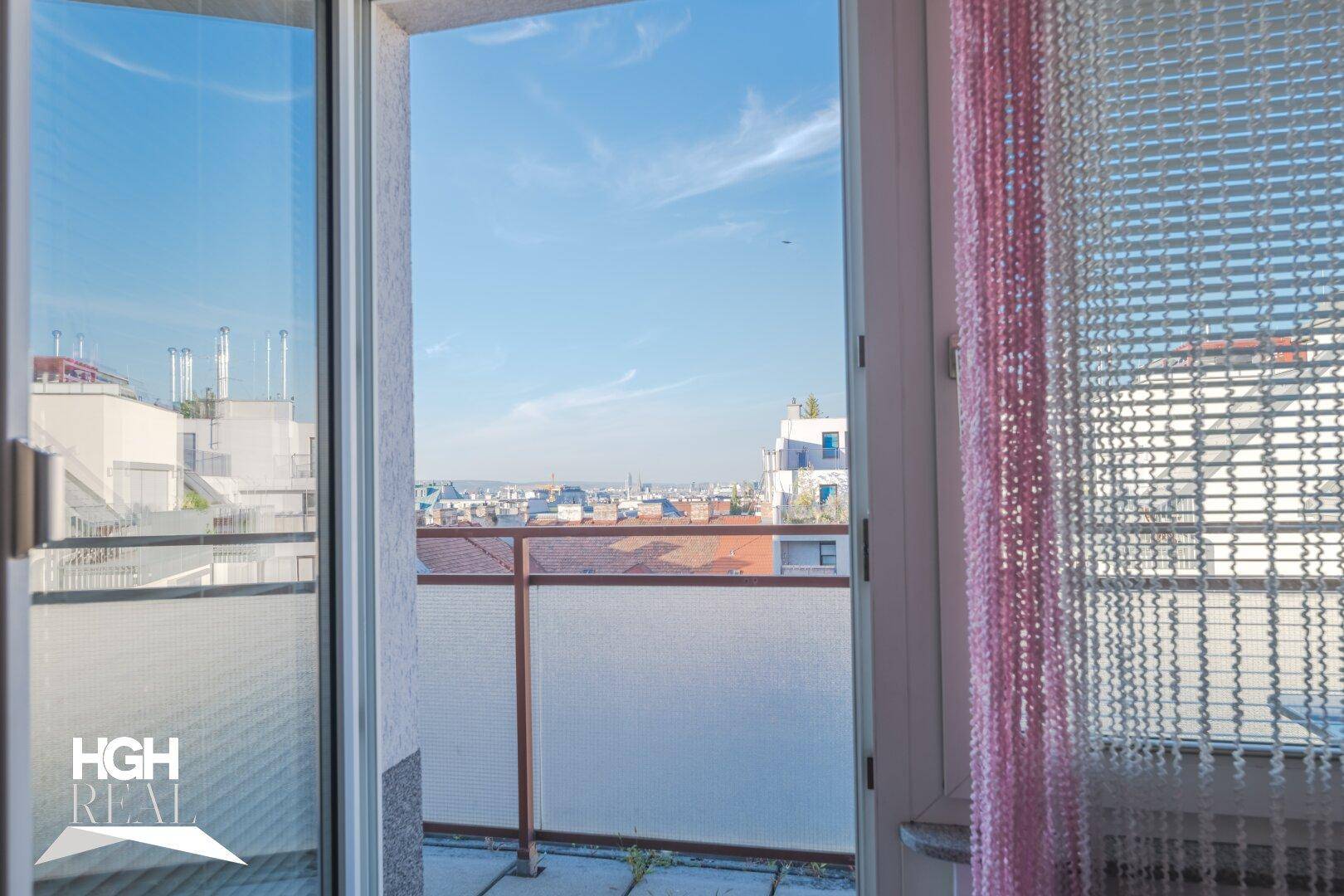 Blick von einem Balkon auf die Stadtlandschaft unter blauem Himmel.