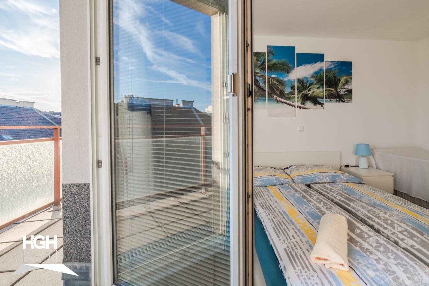 Helles Schlafzimmer mit Zugang zum Balkon und tropischem Wandbild.