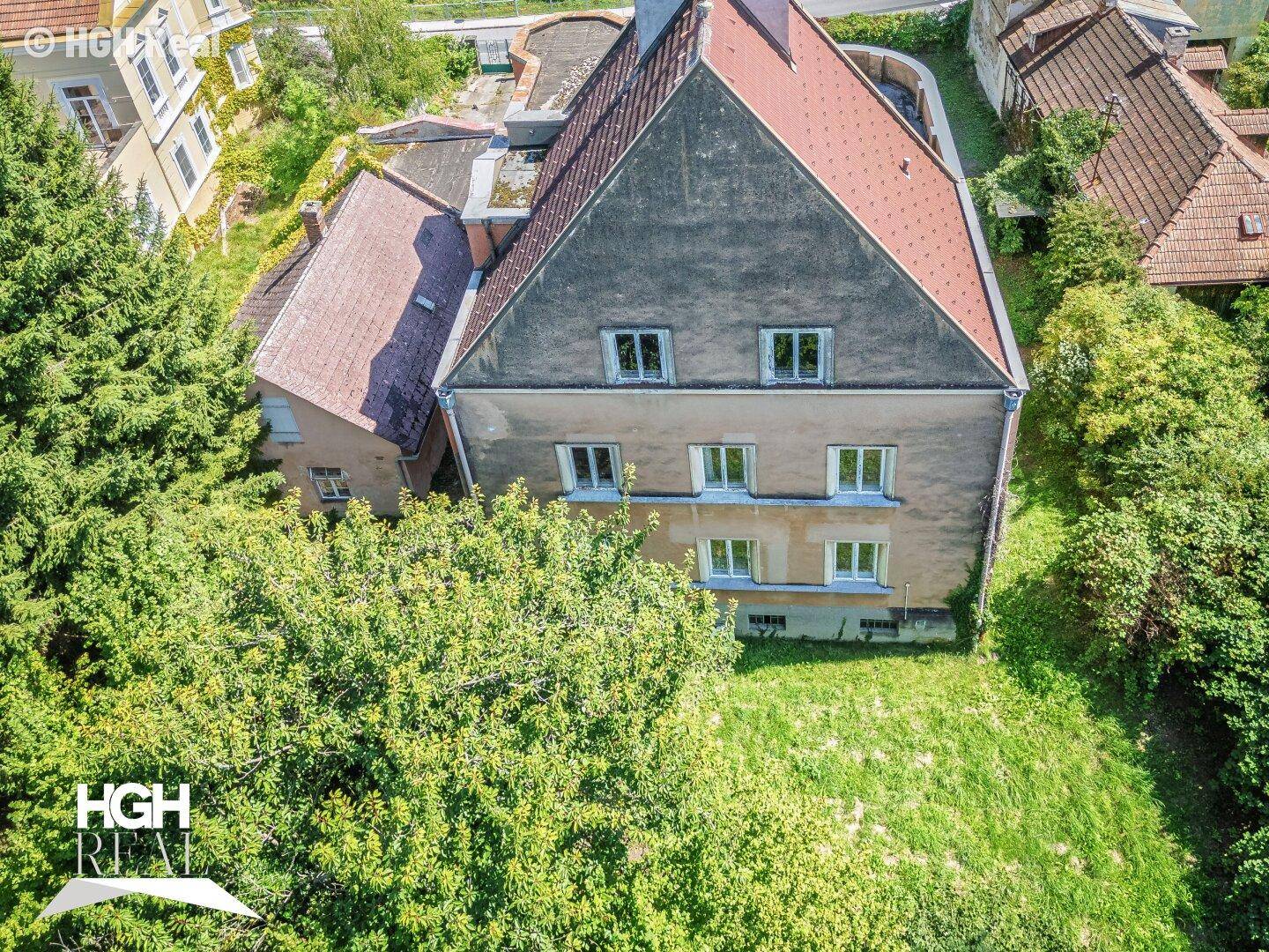 Rückansicht des Gebäudes von oben mit Dach und umliegender Vegetation.